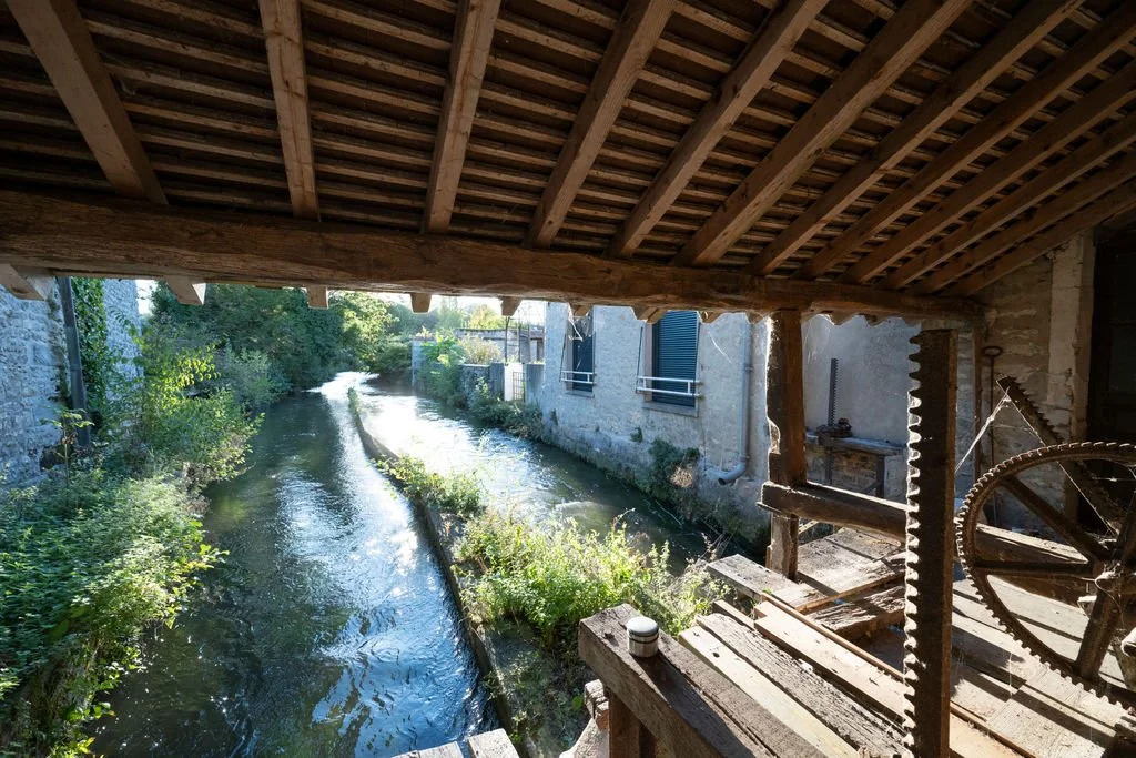 View from inside a wooden structure overlooking a narrow canal with buildings on the opposite side.