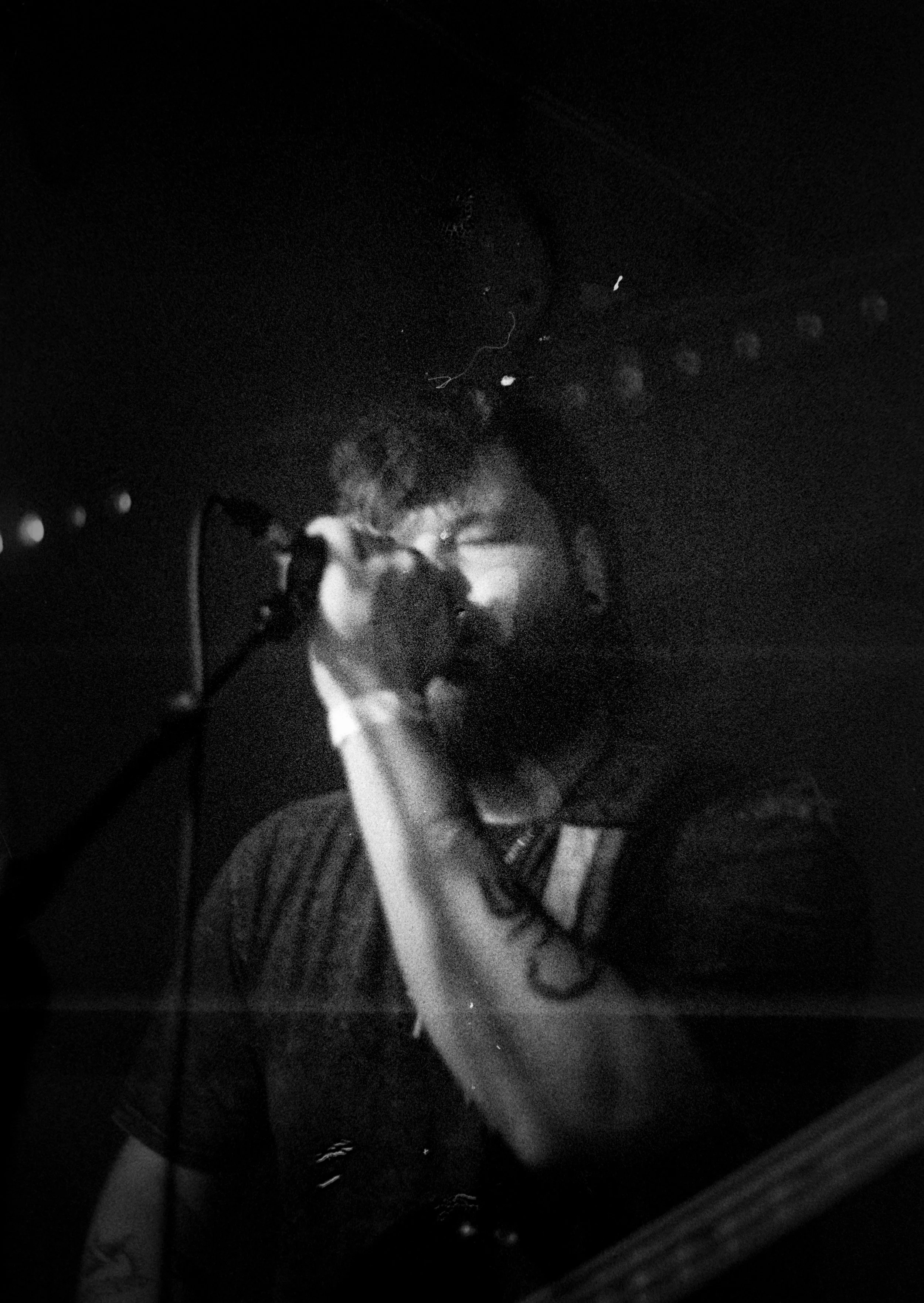 A person singing into a microphone with a dark background.