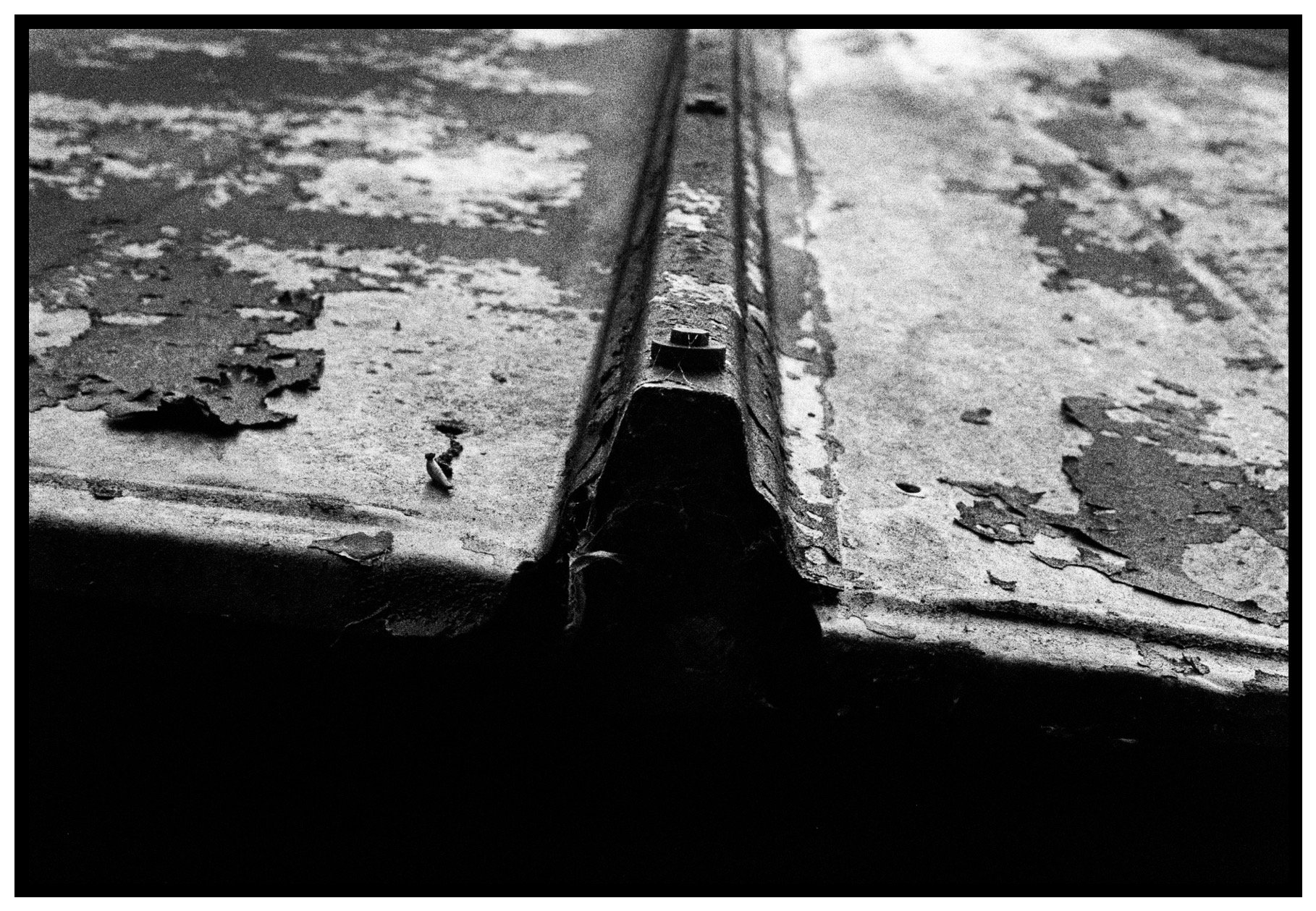 Close-up of a weathered, rusted metal gutter with peeling paint on a roof surface.