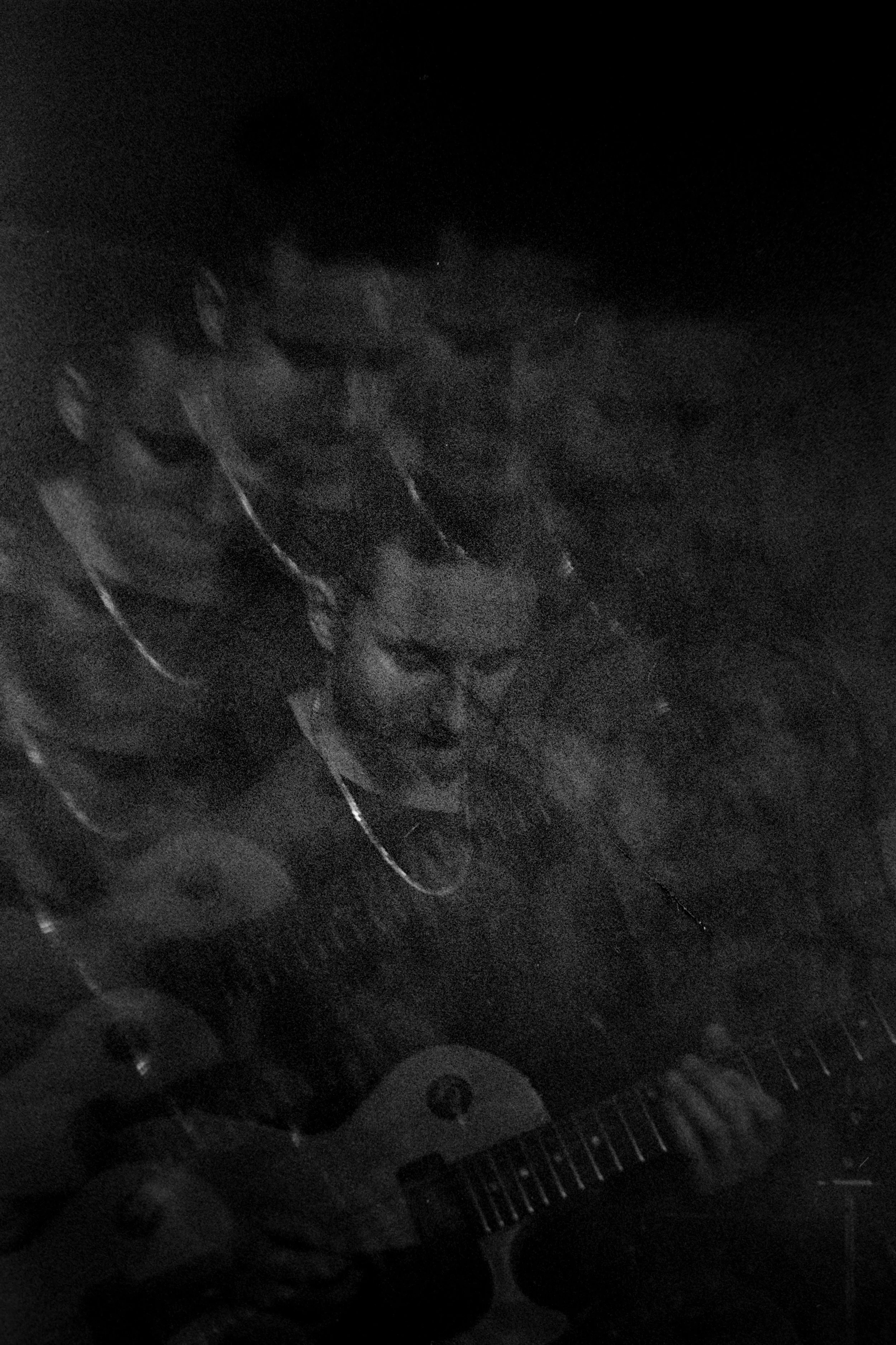 A person playing an electric guitar in a dark setting.