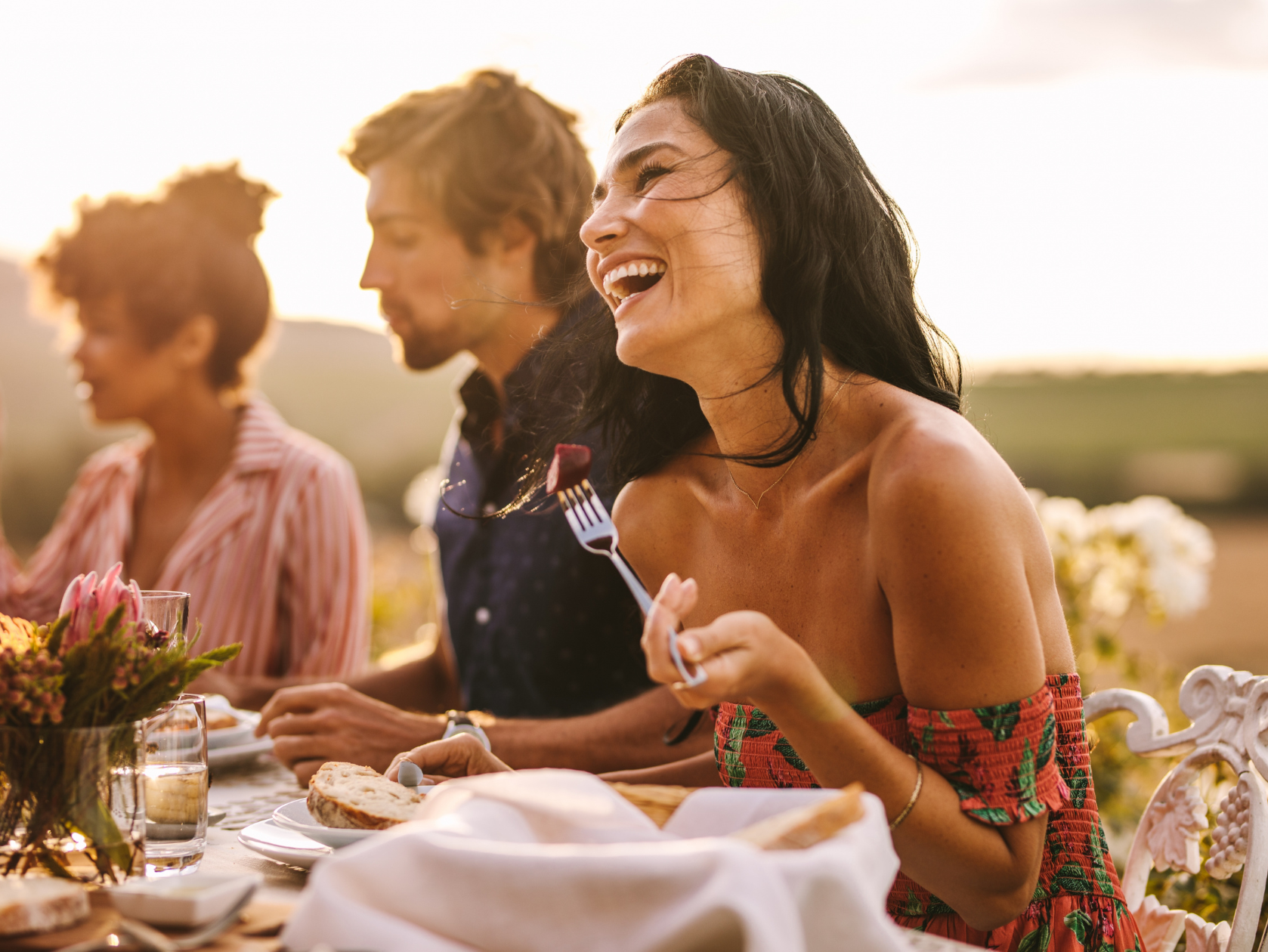 A woman enjoying time with friends at an outdoor dinner party