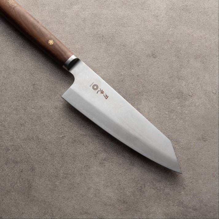 A Japanese kitchen knife with a wooden handle and a stainless steel blade, resting on a textured surface.