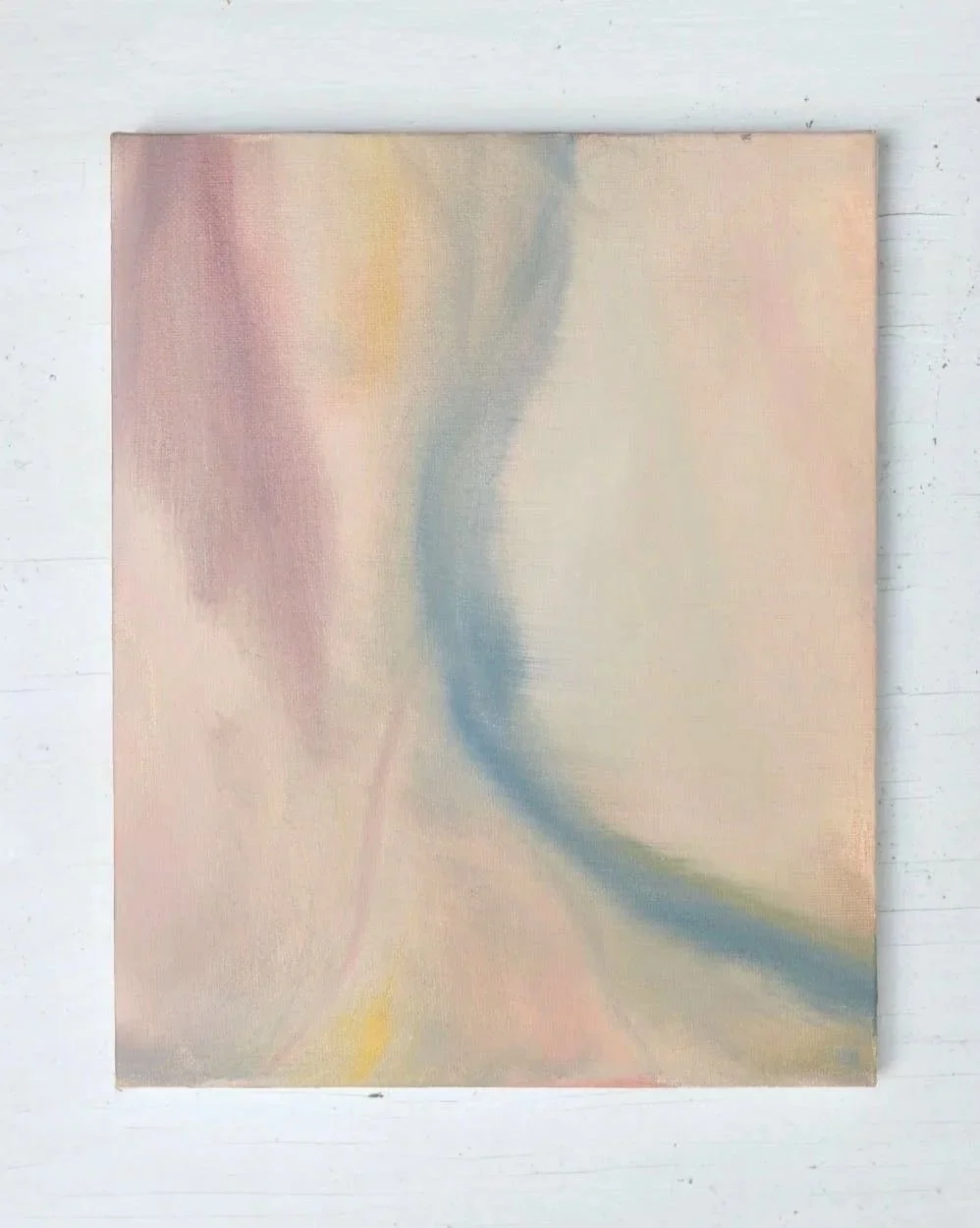 abstract painting showing sandy beige background, a blurred blue line and areas of yellow and burgundy