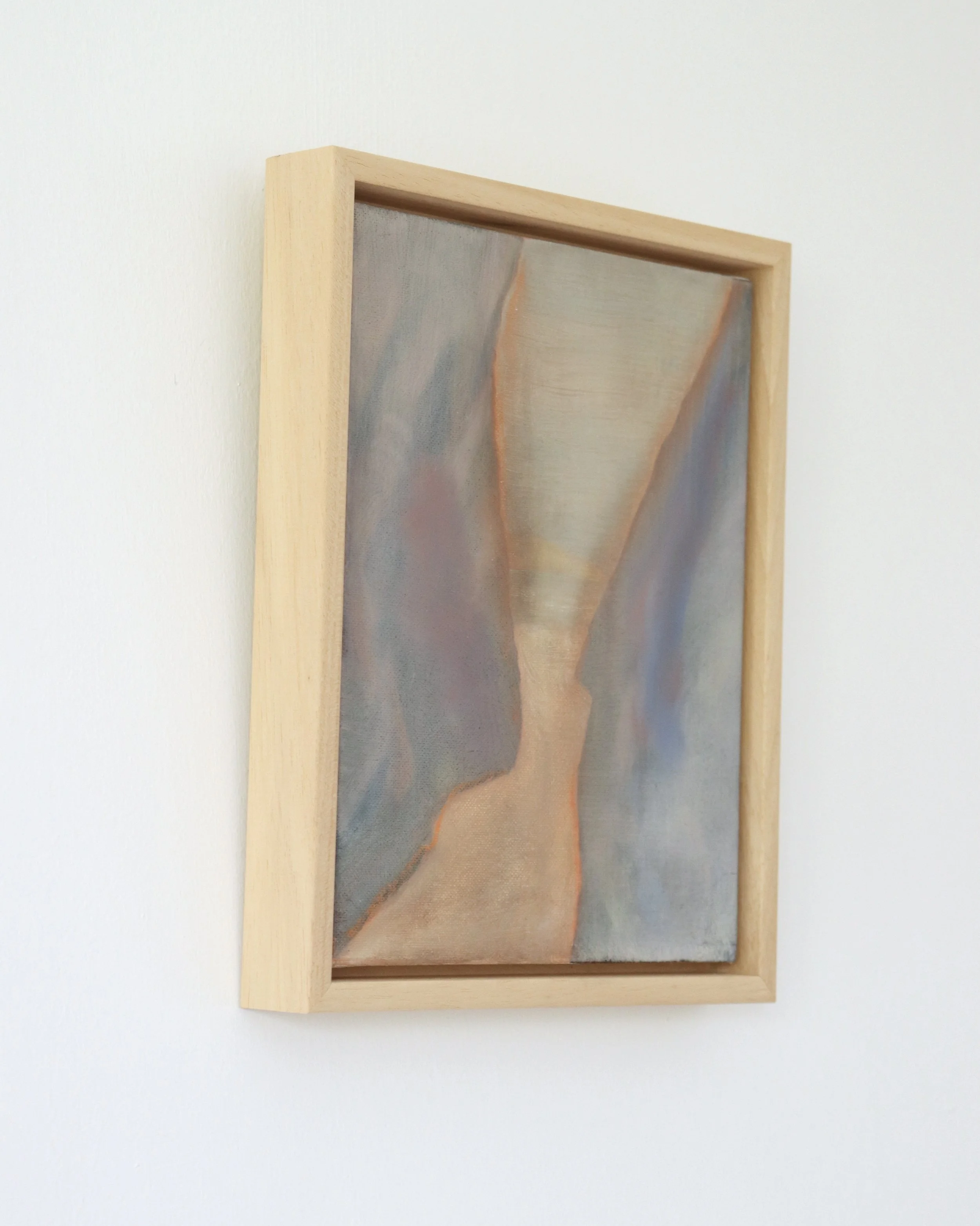 side view of framed painting showing a view between two rock faces