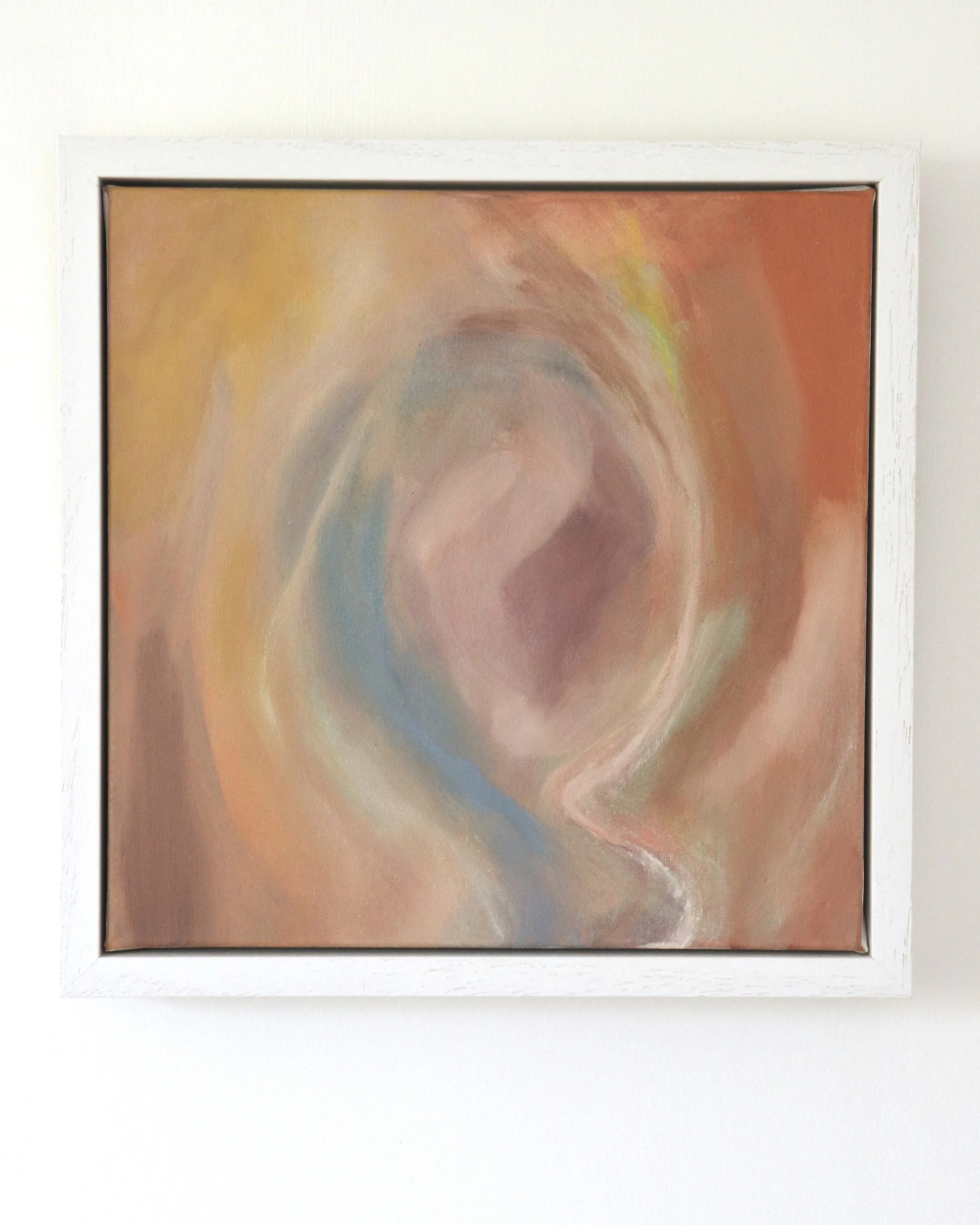 square painting in white frame, colourful abstract depicting a womb like image with orange, pink, blue and yellow colours