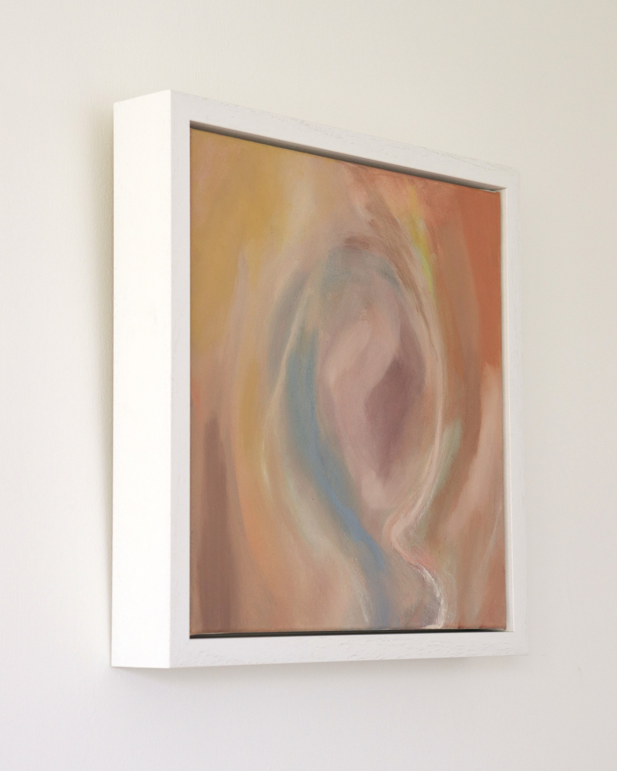 square painting in white frame, colourful abstract depicting a womb like image with orange, pink, blue and yellow colours
