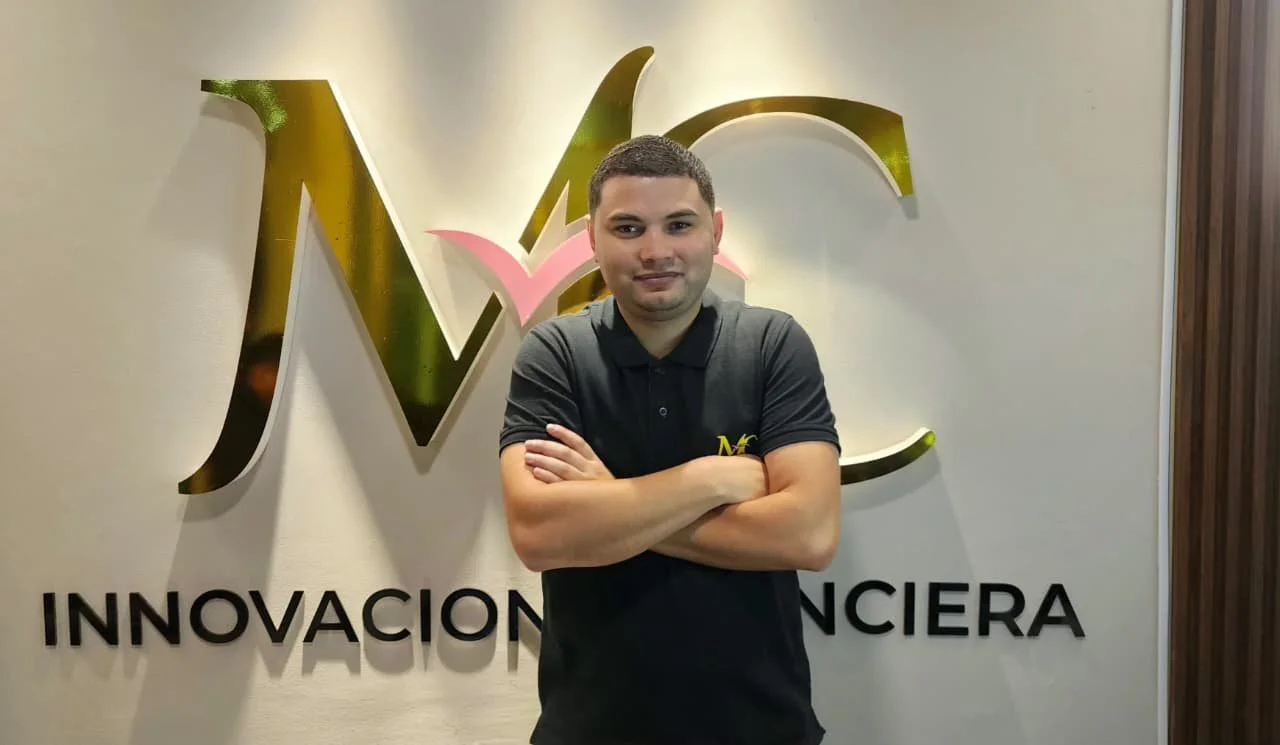 Hombre con camisa negra posando con brazos cruzados frente a un logo y cartel de la empresa 'Innovación Financiera'.