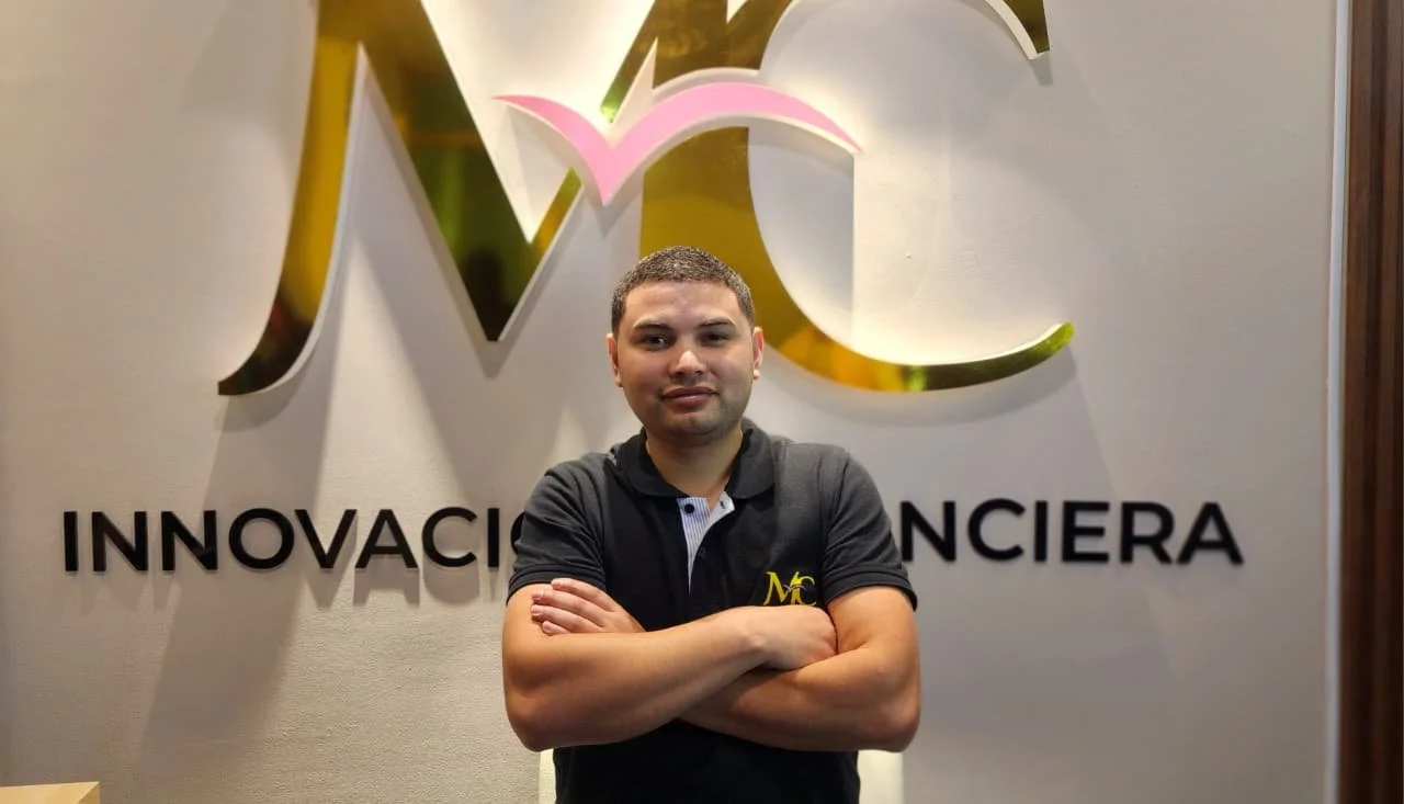 Hombre con camiseta negra y fondo de logo con letras en un muro