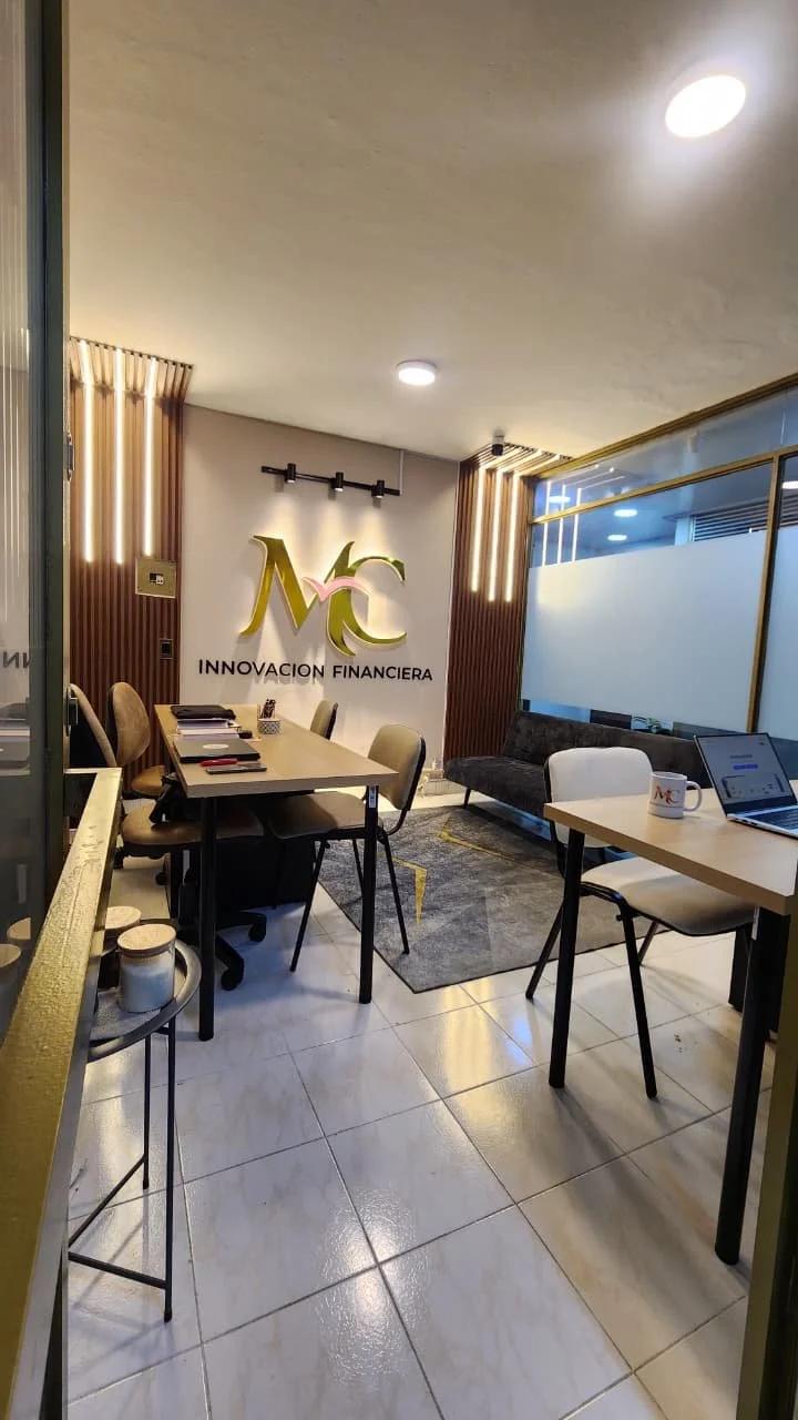 Sala de reuniones con logo de 'Innovacion Financiera' en la pared, mesa de reuniones, sillones y una laptop en una mesa con una taza