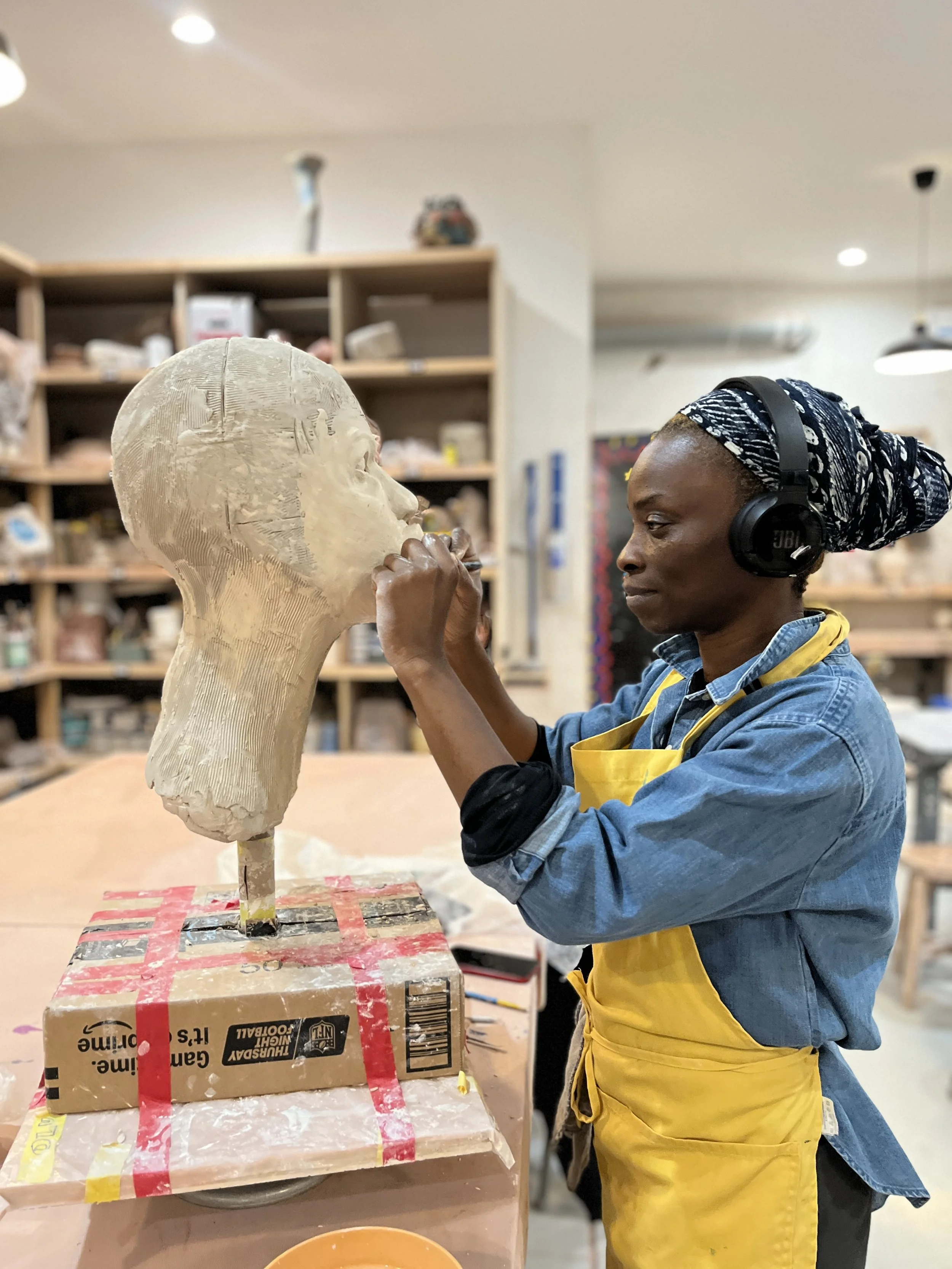 A woman working on a scuplture made of clay