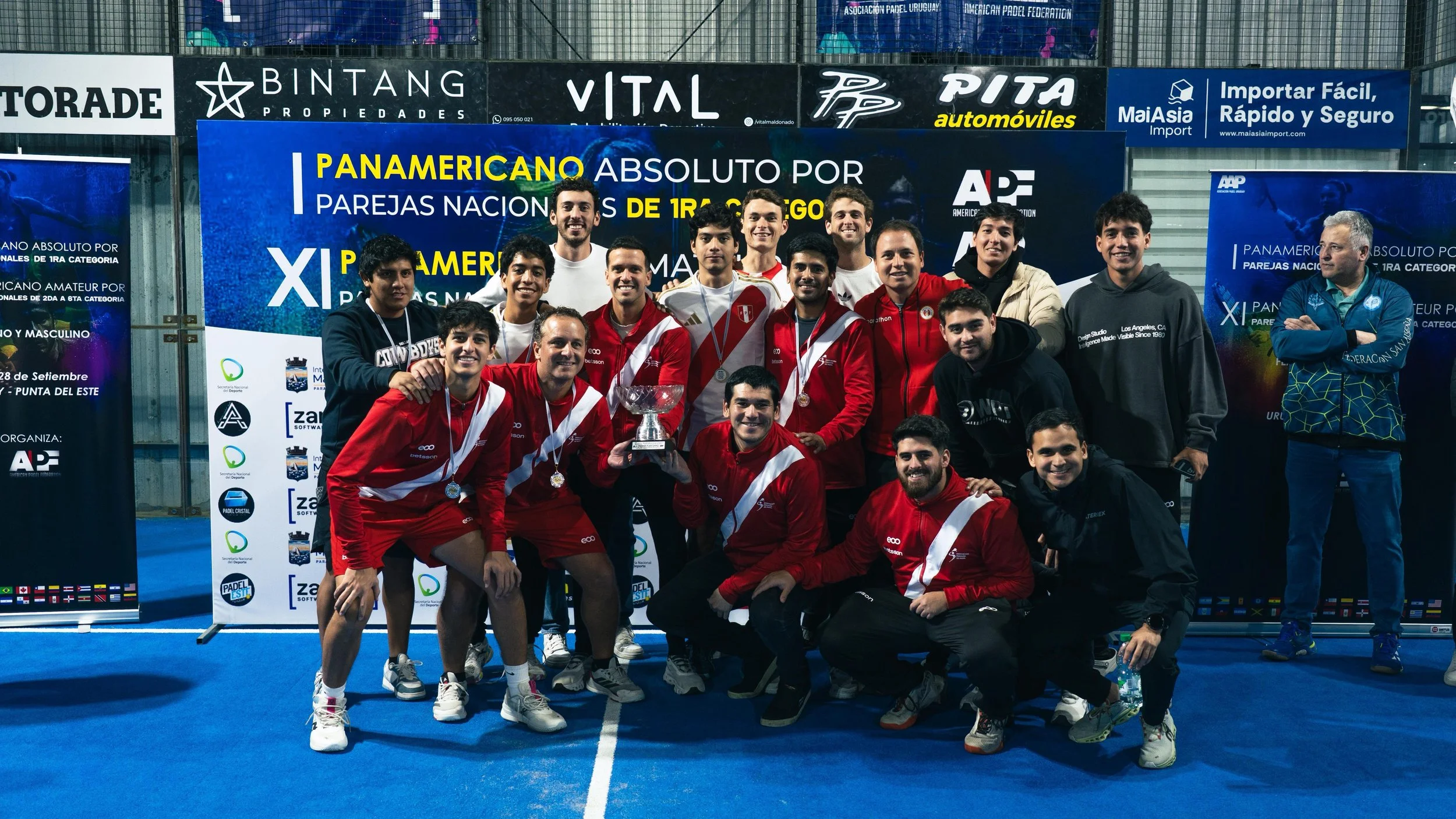 Grupo de jugadores de pádel en uniforme rojo y blanco celebrando con trofeo en un torneo nacional en Uruguay.