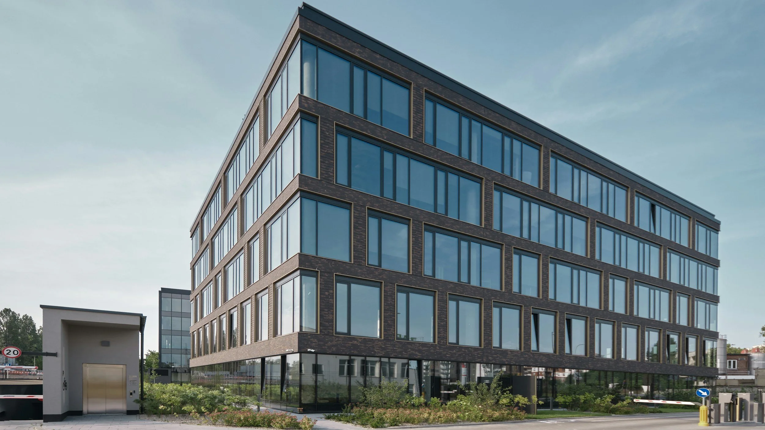 Modern multi-story building with large glass windows and dark brick exterior.
