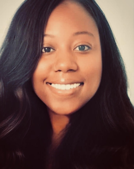 Close-up of a young woman with long black hair smiling against a neutral background.