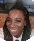 Close-up of a smiling Black woman with braided hair and hoop earrings