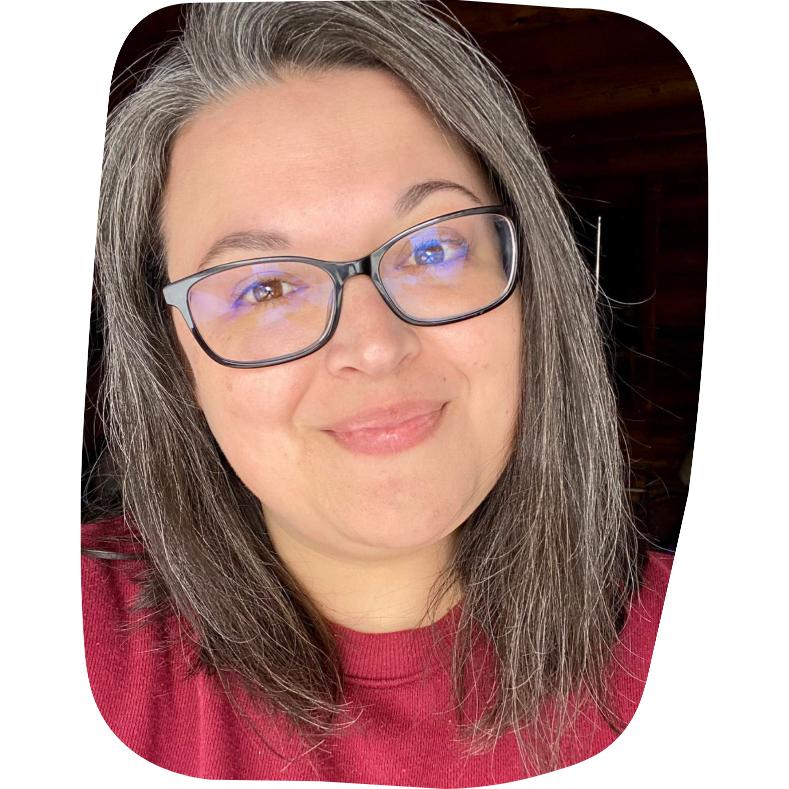 A smiling woman with glasses and long, wavy hair wearing a red top