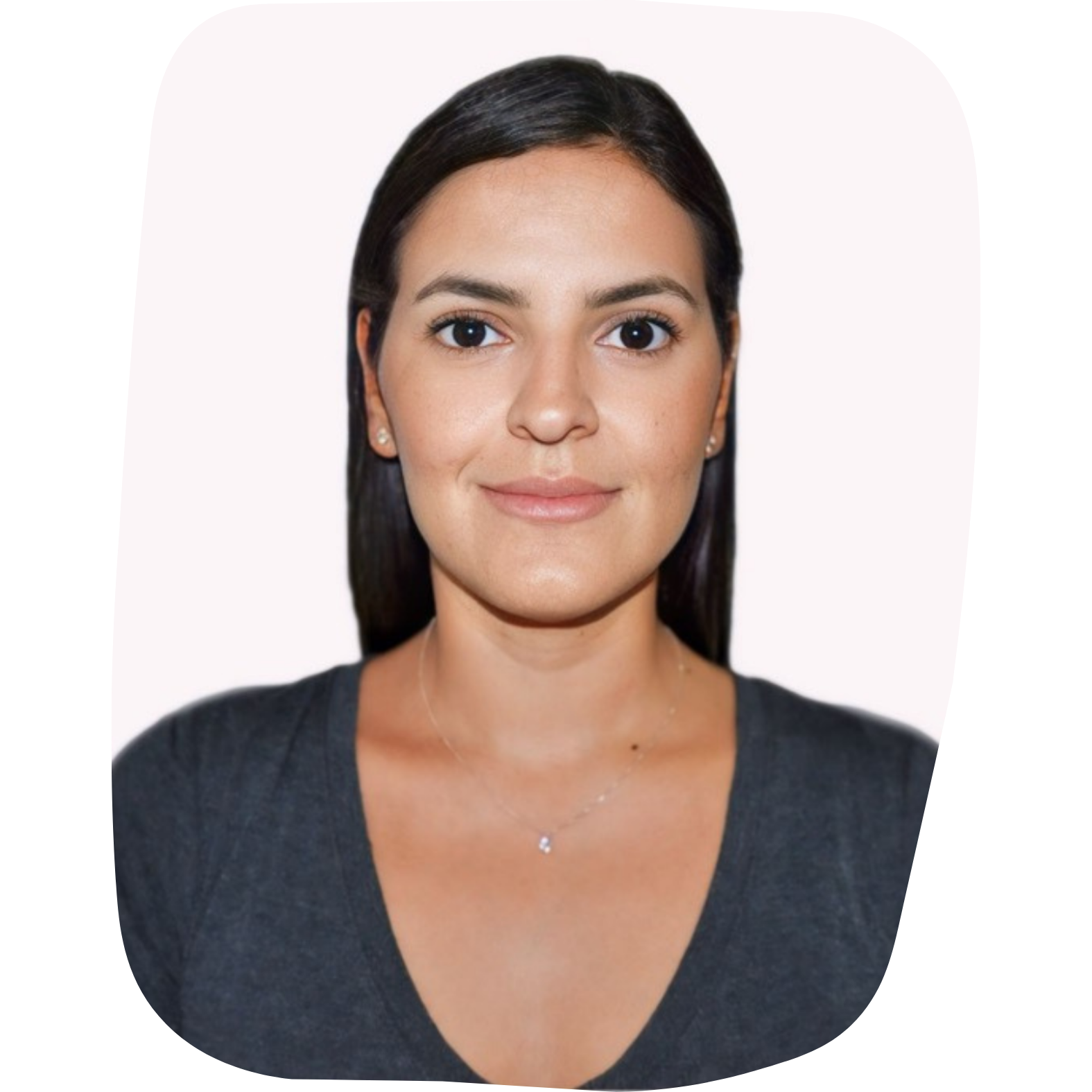 Head and shoulders portrait of a woman with dark hair, wearing a dark grey top and a delicate necklace, smiling softly against a plain light background.
