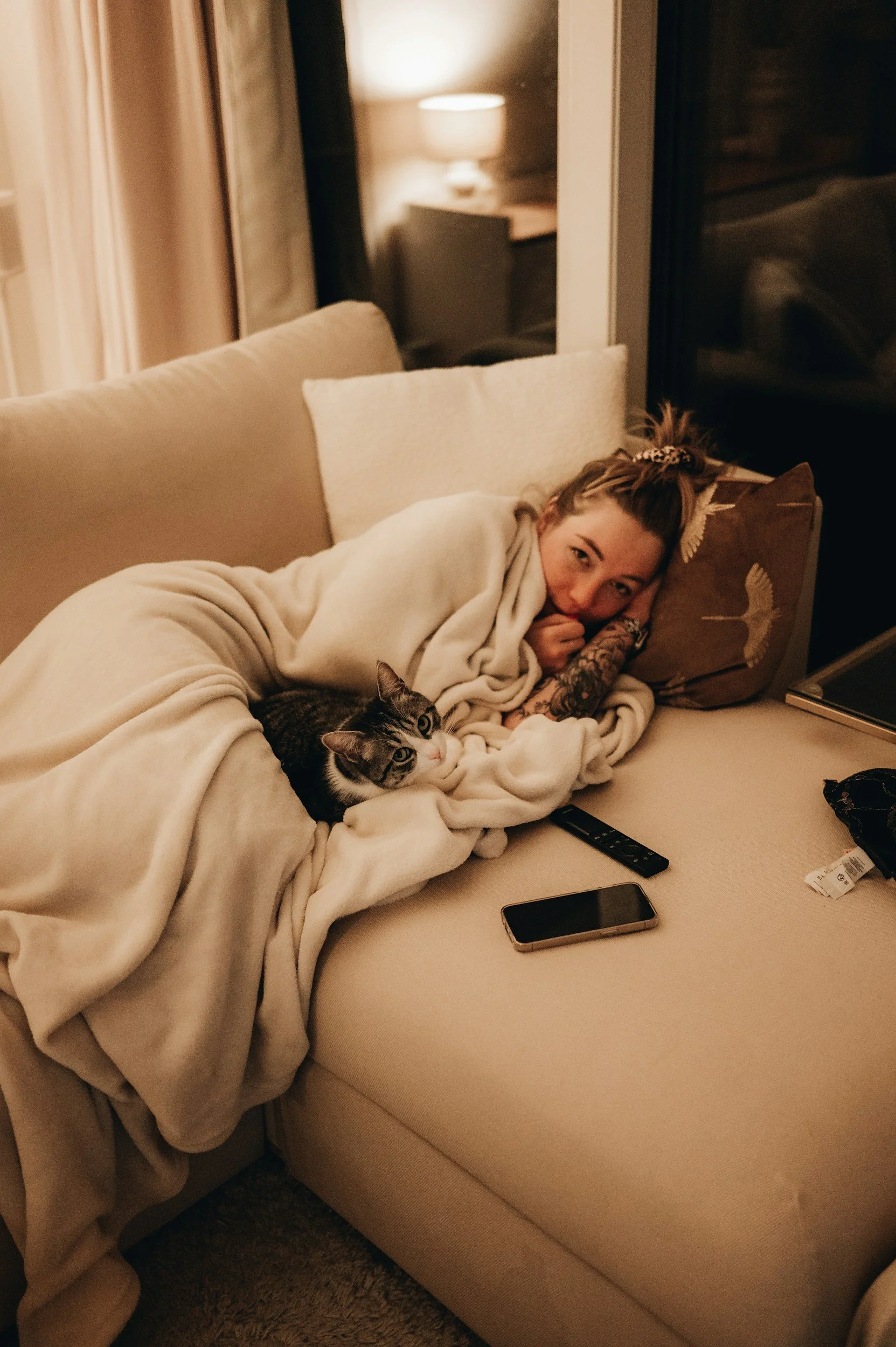 Woman on couch with cat and phone, representing the Cove Collective online infertility support group experience — available 24/7, no Zoom calls required.