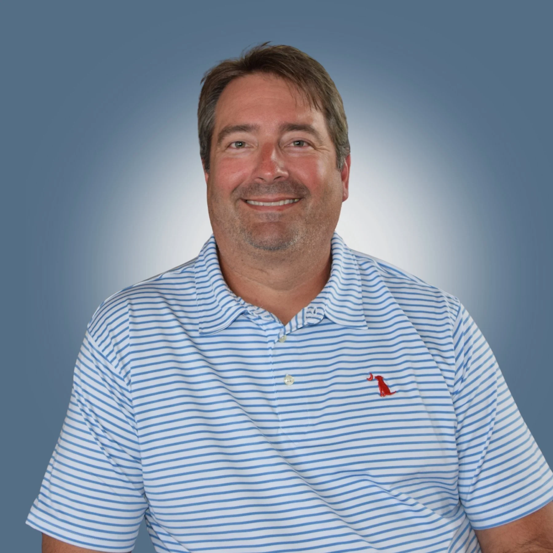 A smiling man with brown hair, wearing a blue and white striped polo shirt, against a gradient blue background.