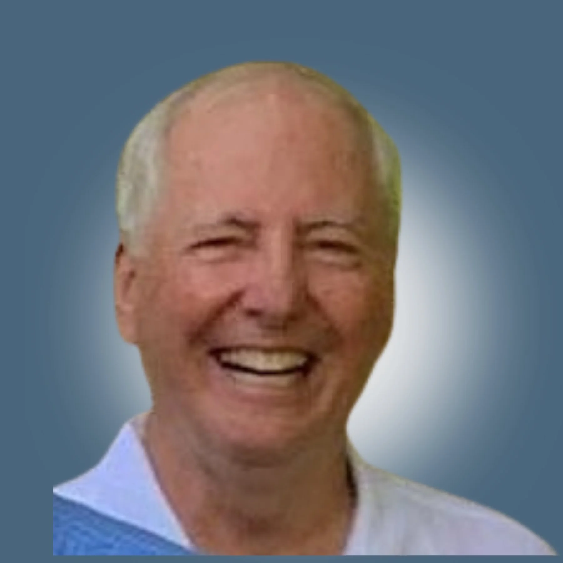Smiling elderly man with short gray hair, wearing a white shirt, against a blurred blue background.