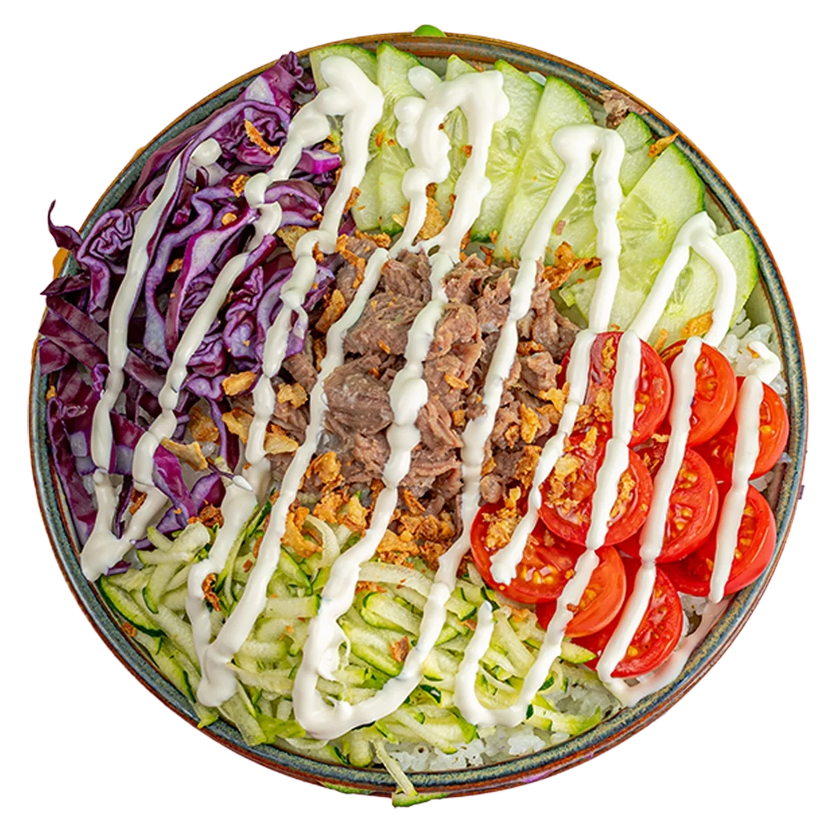 Buddha bowl with purple cabbage, sliced cucumbers, cherry tomatoes, shredded lettuce, shredded zucchini, shredded carrots, shredded meat, and a drizzle of white dressing.