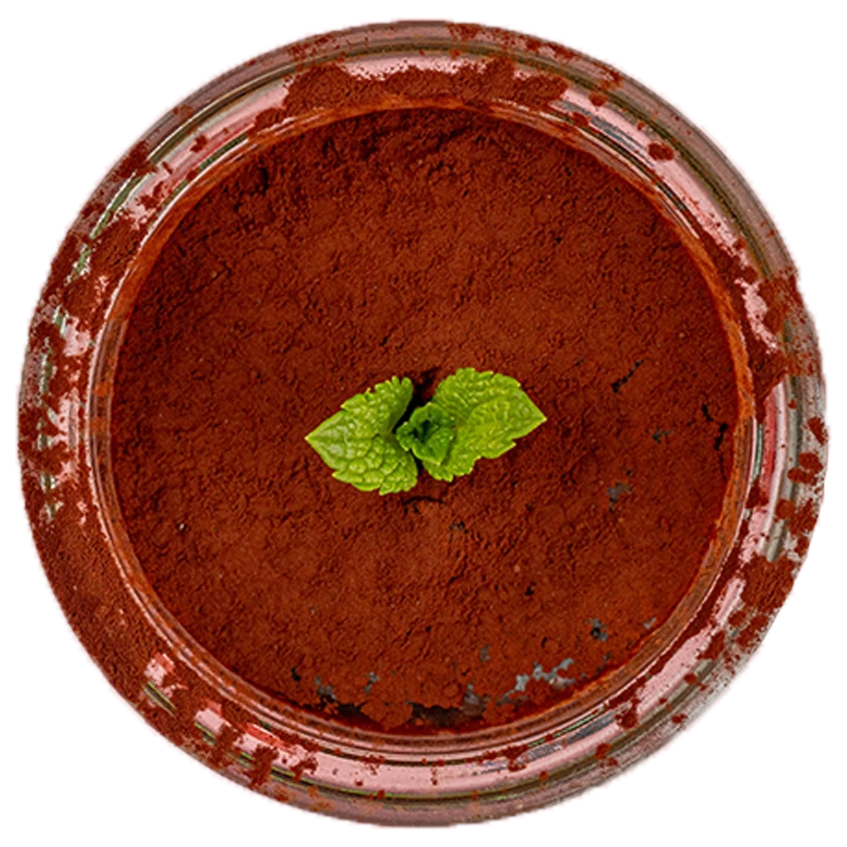 A glass jar filled with cocoa powder garnished with a small sprig of green mint leaves on top.