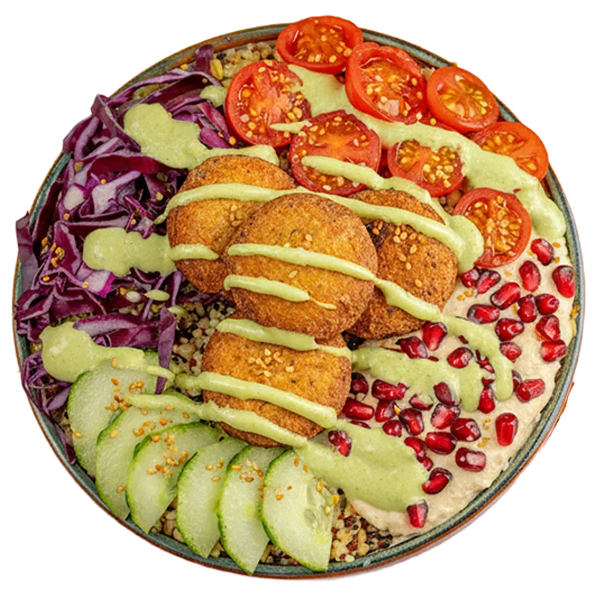 A colorful bowl of vegetarian Mediterranean-style platter featuring sliced cucumbers, halved cherry tomatoes, red cabbage, falafel patties with drizzled green sauce, sprinkled pomegranate seeds, and a side of hummus garnished with red pepper flakes.