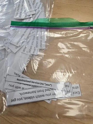 A ziplock bag contains cut sheets of paper: versions of spoken-like sentences and written-like (formal) versions. Students use these to complete the deconstruction activity.