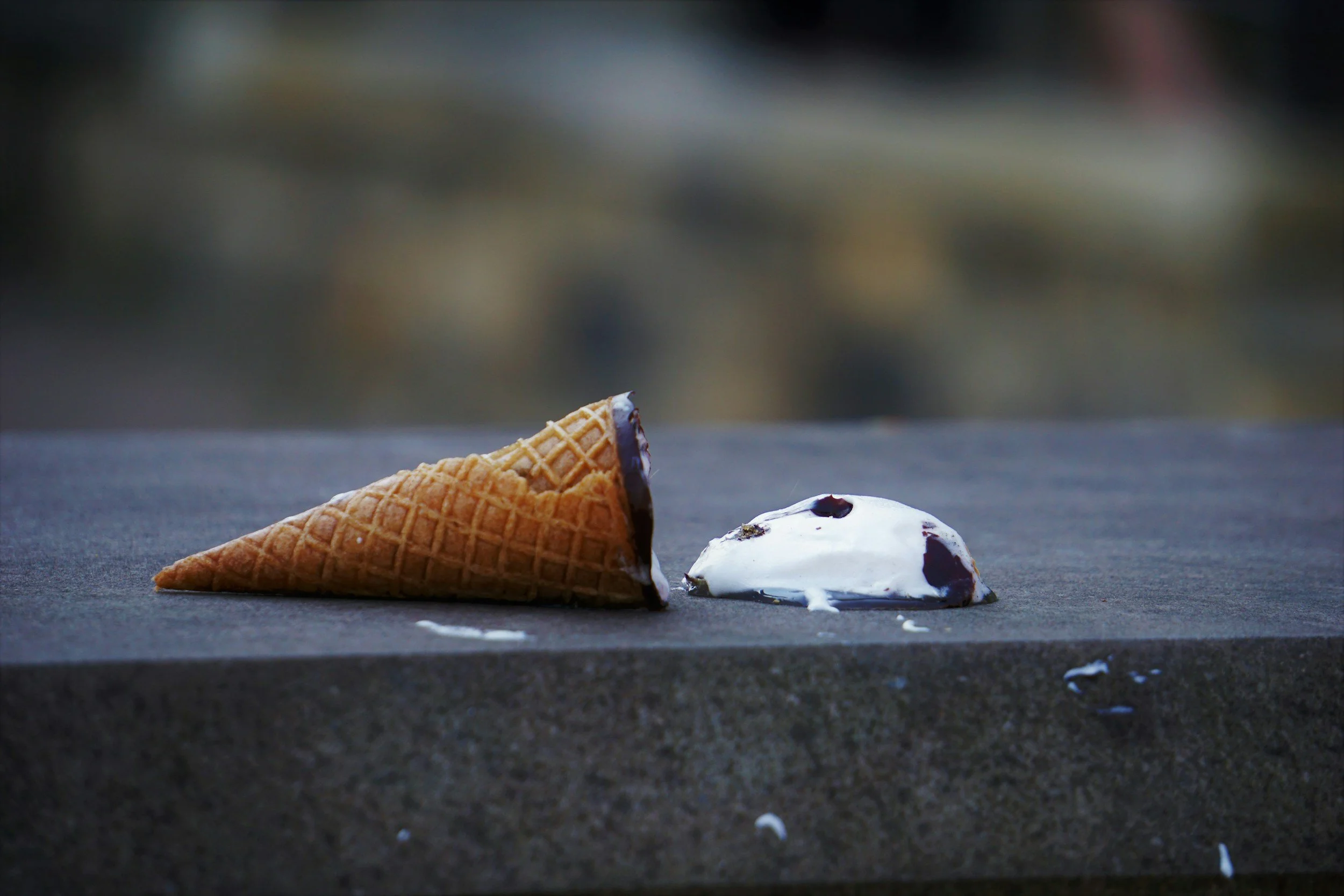 Spilled ice cream with chocolate cone on a concrete surface