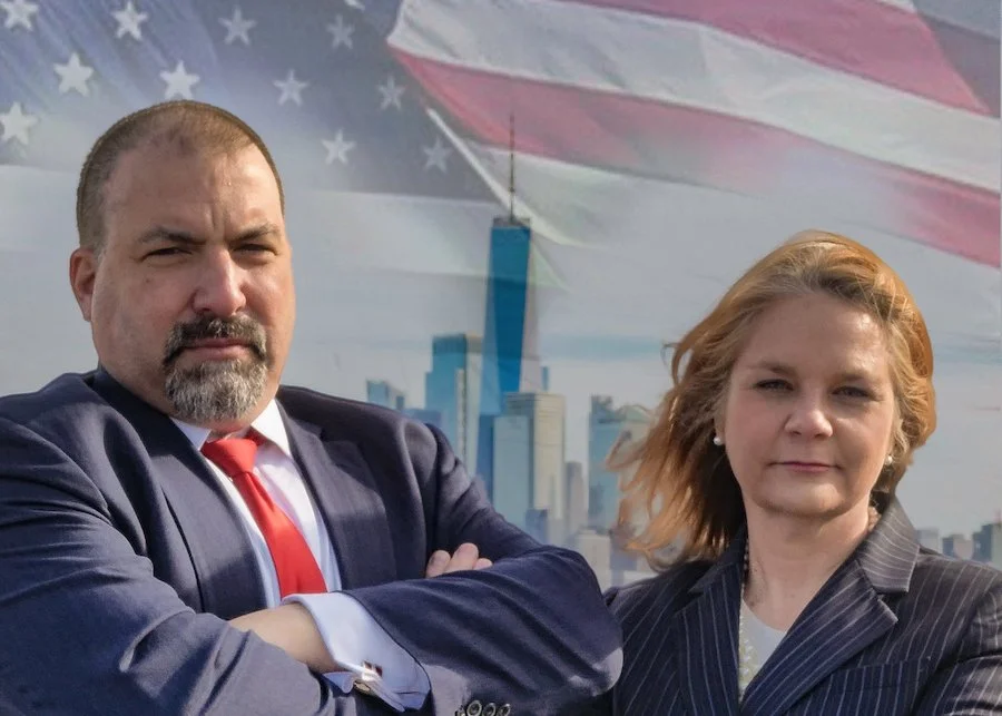 Lawyers Ron Berutti and Gwyneth Murray-Nolan in front of NYC scene and flag.