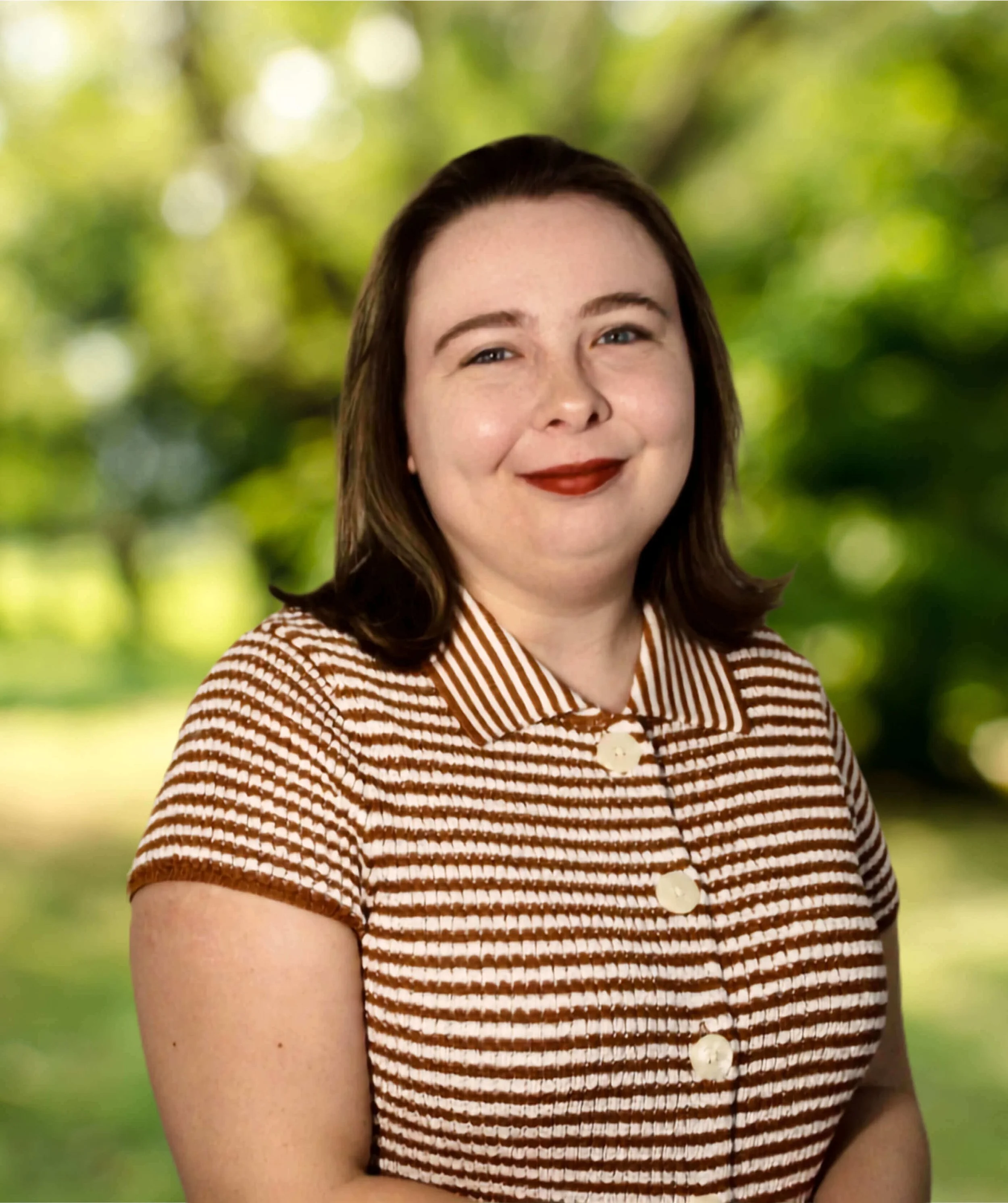 Sara Buchanan: Young white female therapist smiling at the camera, wearing a white and brown striped shirt, in front of blank off white background