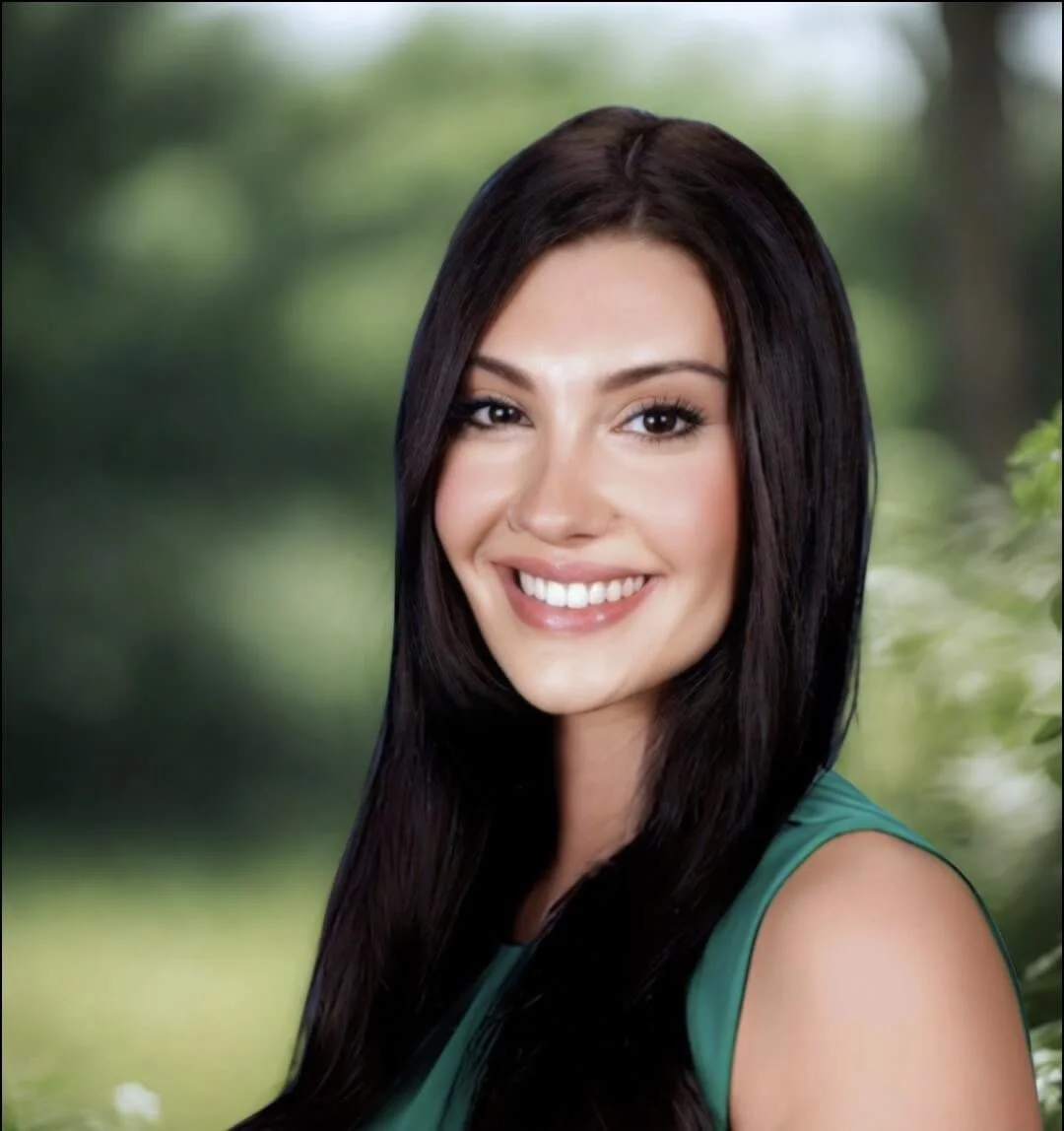 Mackenzie Fezza Headshot: A smiling female therapist with long dark hair and a green sleeveless top outdoors with a blurred green background.