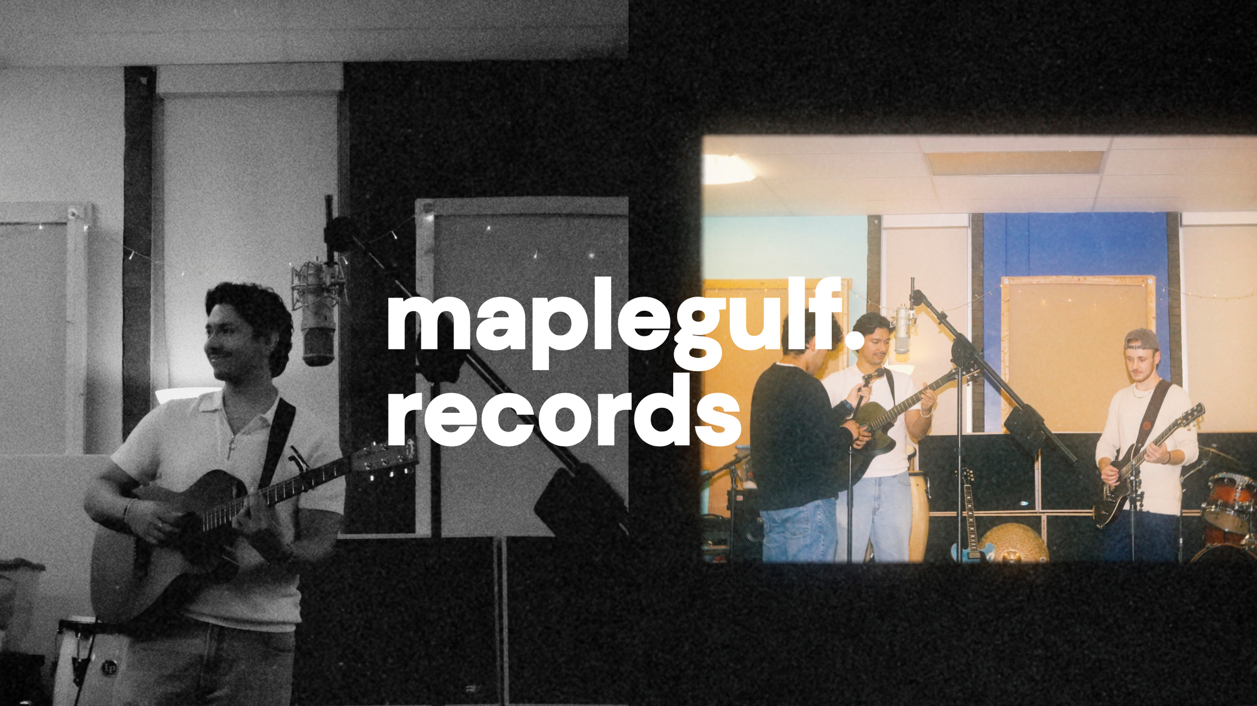 A black and white photo of a man with dark hair playing an acoustic guitar and smiling, in a recording studio. In the background, through a window, a group of three people are playing instruments and singing into a microphone, with color flashing walls behind them.
