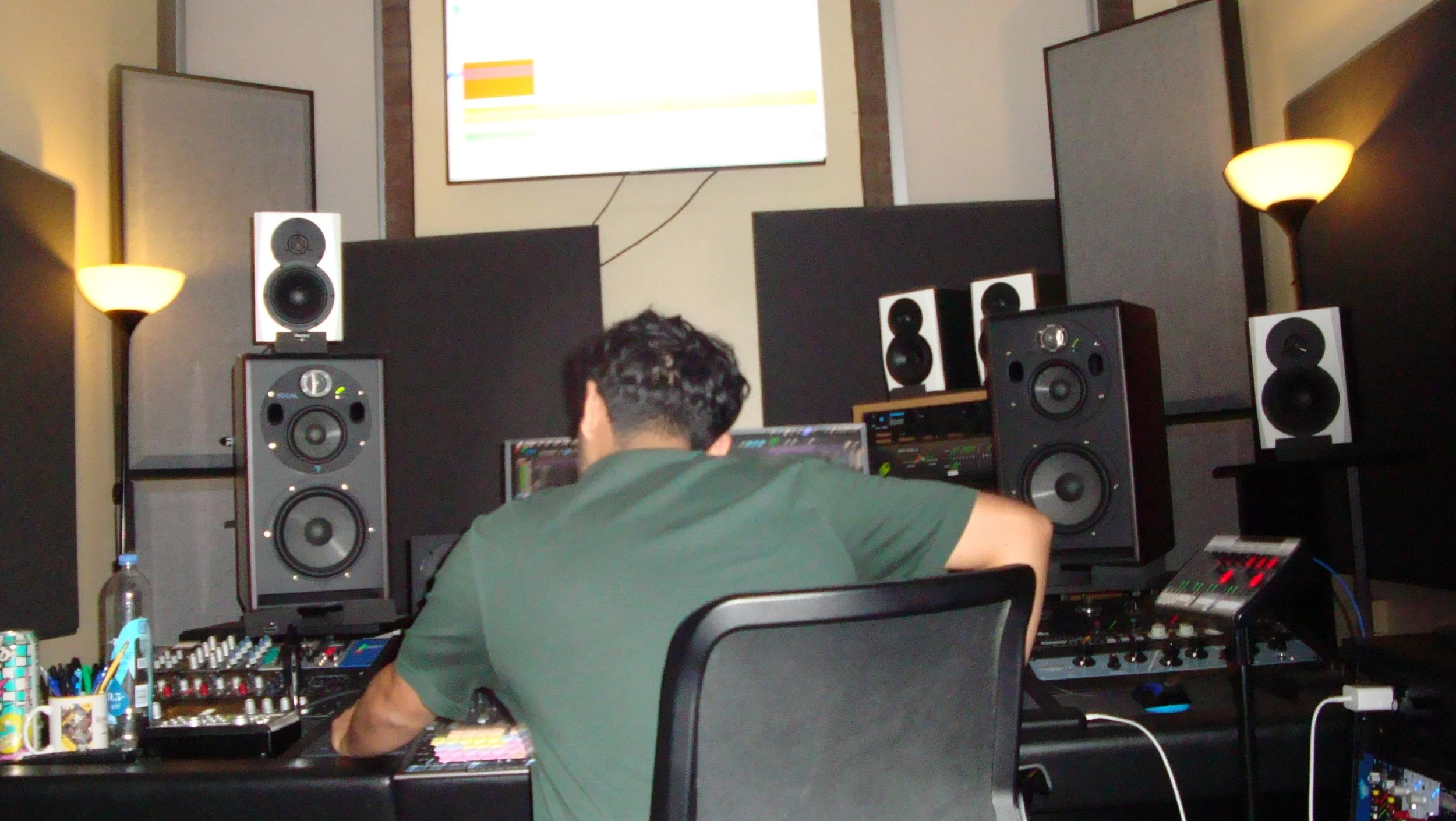 A person working in a music studio surrounded by professional speakers and sound equipment.