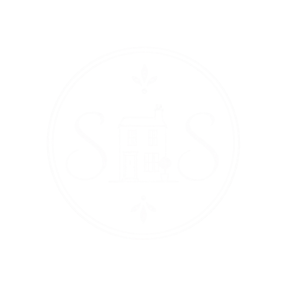 A black and white image of a clock face with ornate details, featuring Roman numerals and decorative elements.
