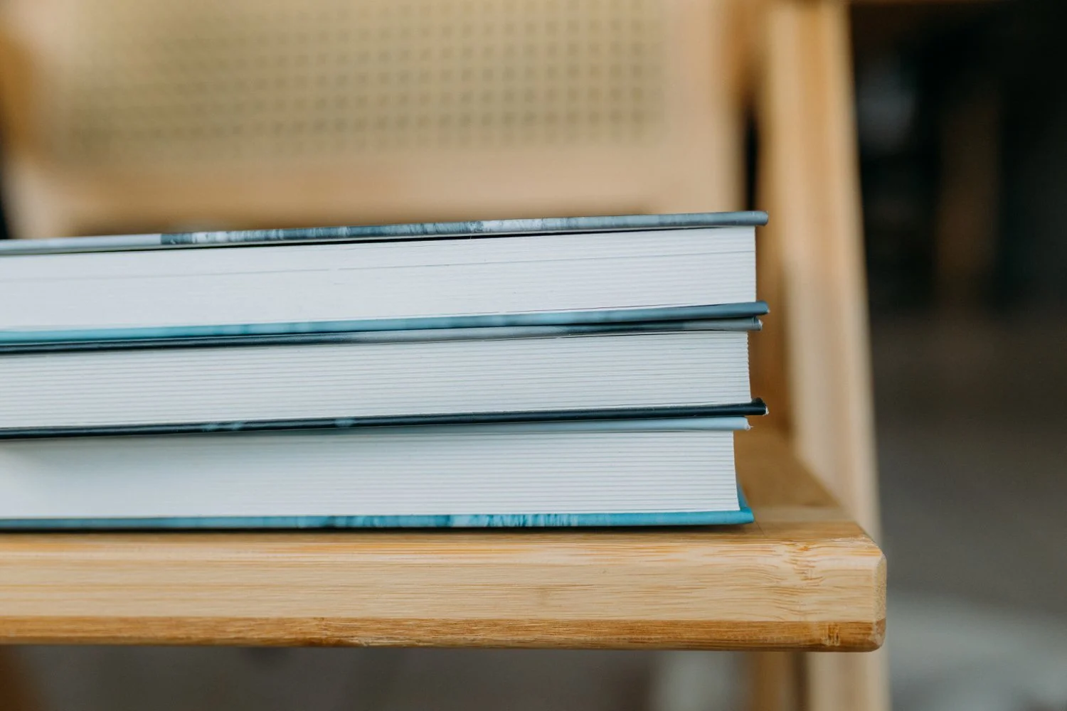Drei Alben liegen auf einem Holztstuhl, im Hintergrund die Stuhllehne.