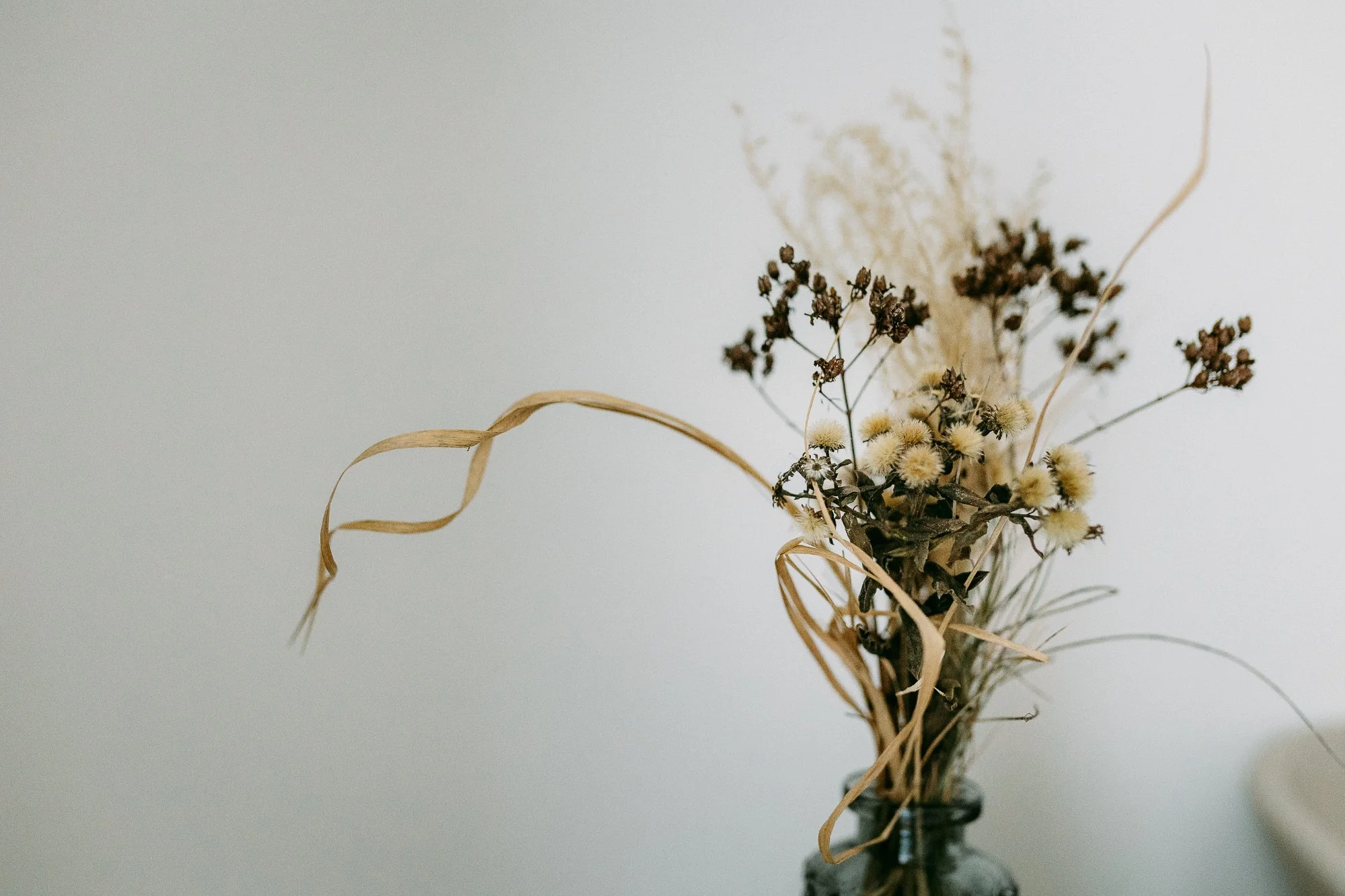Trockenblumenstrauß in einer Flasche, bestehend aus getrockneten Gräsern und Blüten in neutralen Farben.