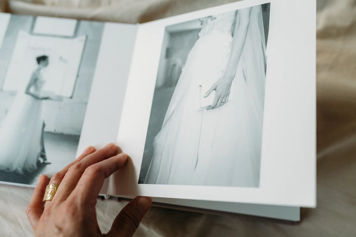 Eine Hand blättert in einem Album mit schwarz-weissen Fotografien. Eher Nahaufnahme.