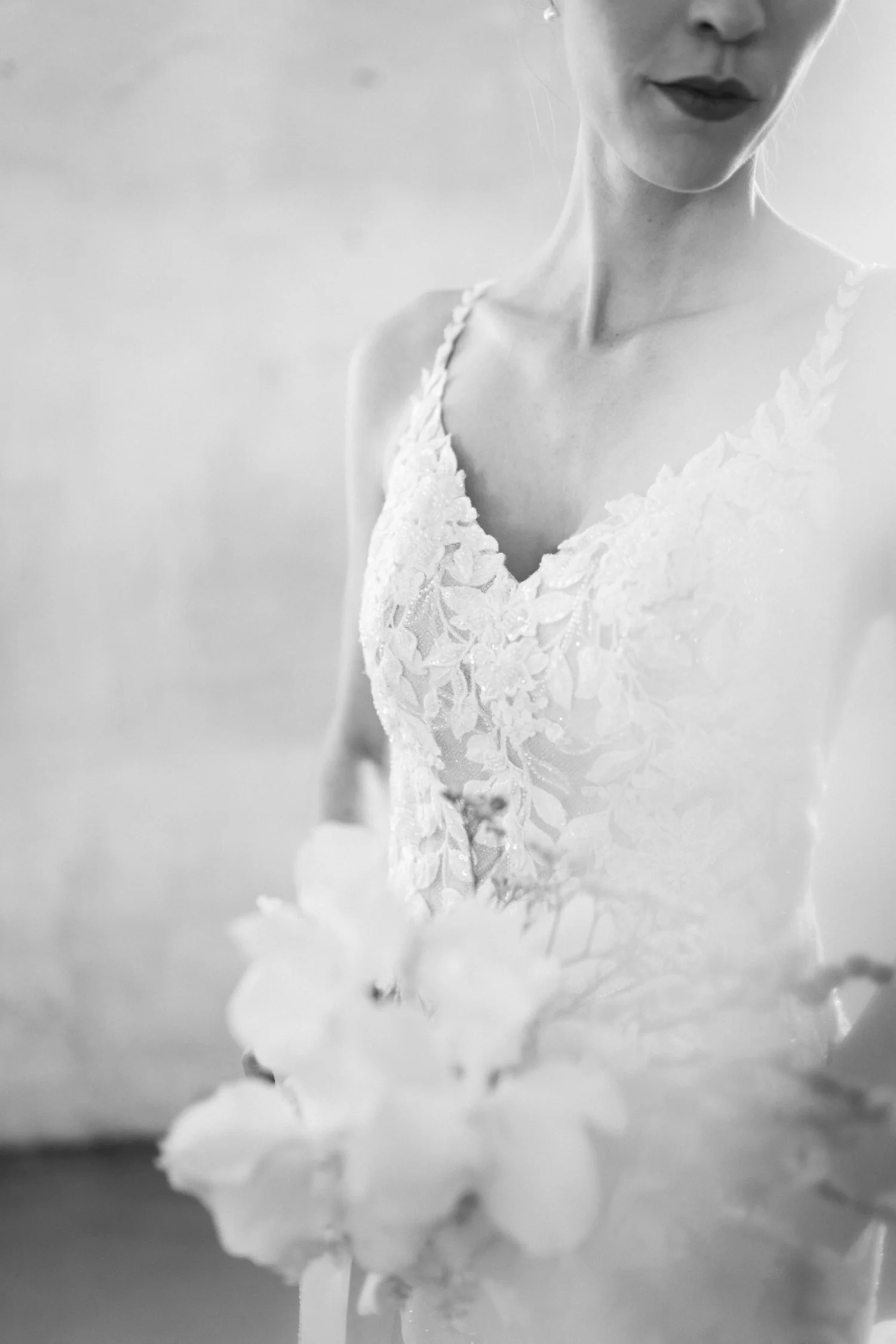 Schwarz-weiss-Fotografie einer Frau im Brautkleid, die ein Bouquet hält.