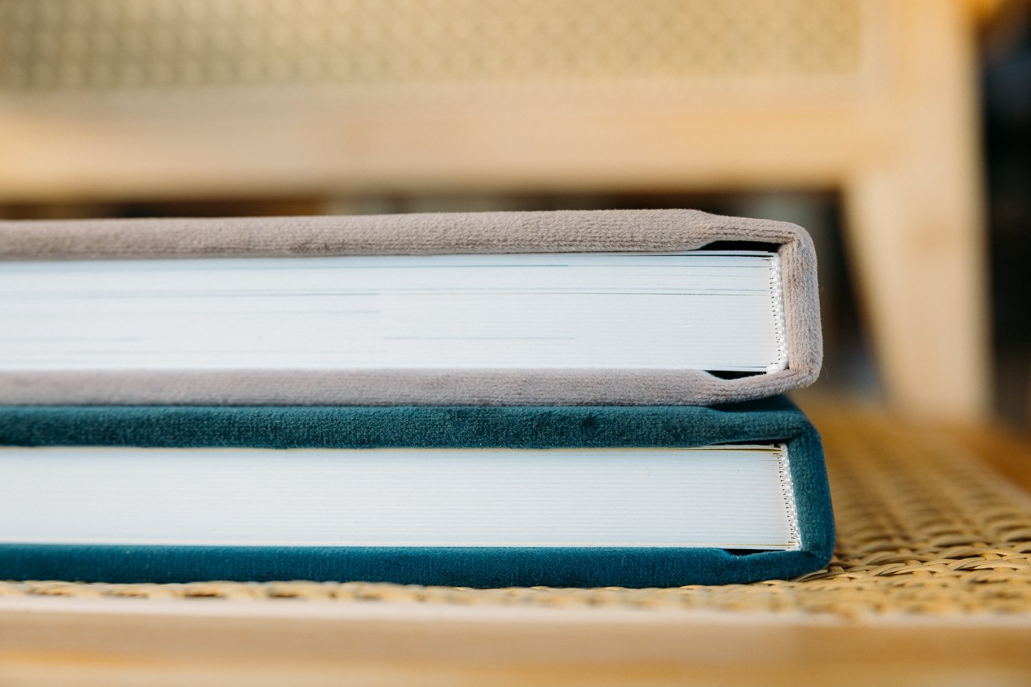 Zwei gestapelte Alben, auf einem geflochtenen Untergrund liegend, Nahaufnahme