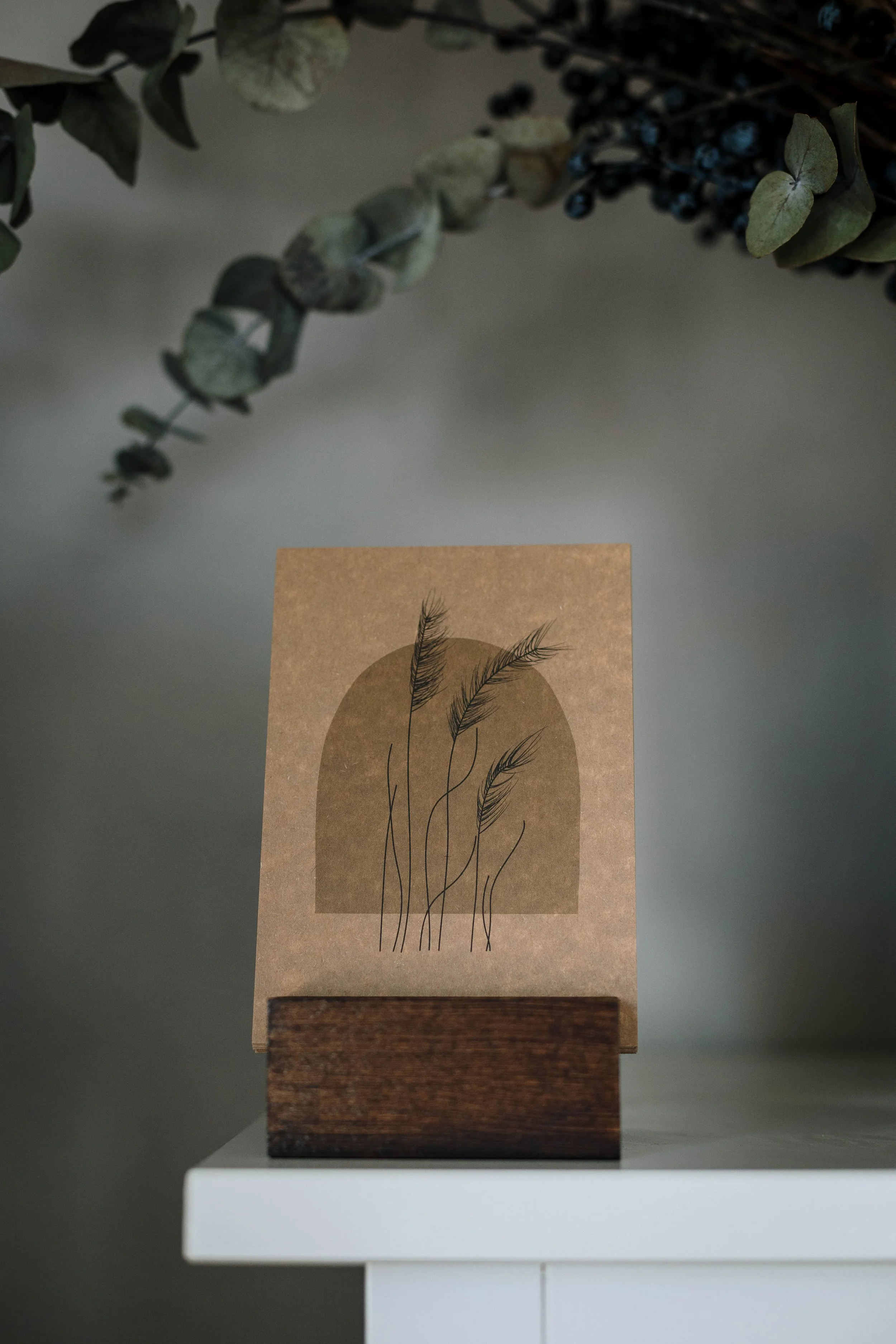 Postkarte aus Kraftpapier mit Pampasgräser auf dem Bild, Eukalyptus im Hintergrund.