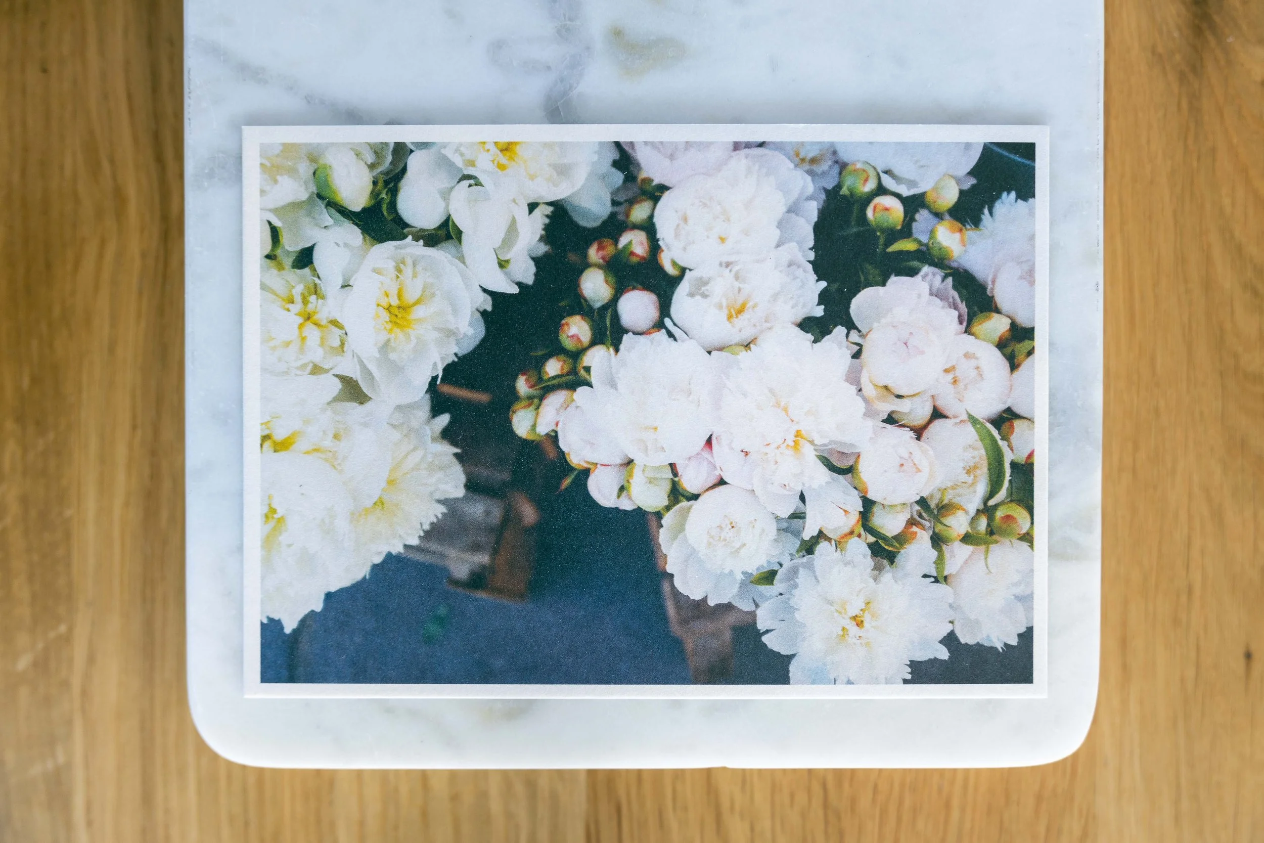 Postkarte auf einem Marmorbrettchen mit Pfingstrosen auf dem Bild.