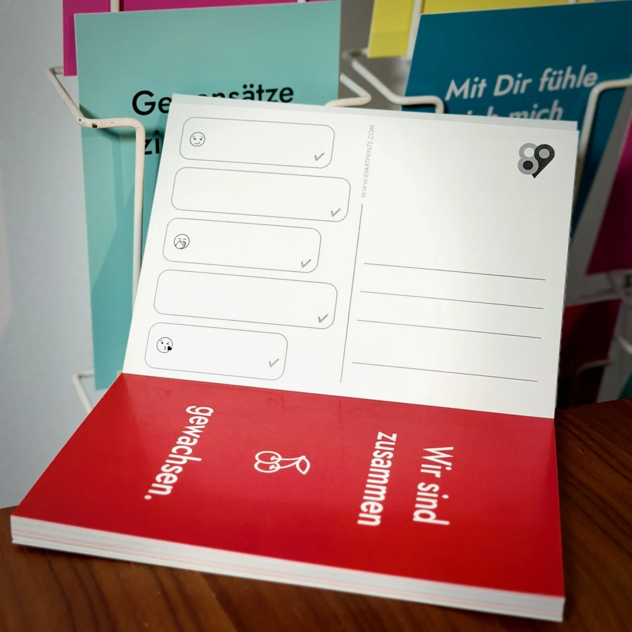 Buch mit 25 Postkarten mit dem Titel 25 Chat Cards. Love Edition. Man sieht die Postkarte "Wir sind zusammengewachsen" und die Rückseite einer Postkartre