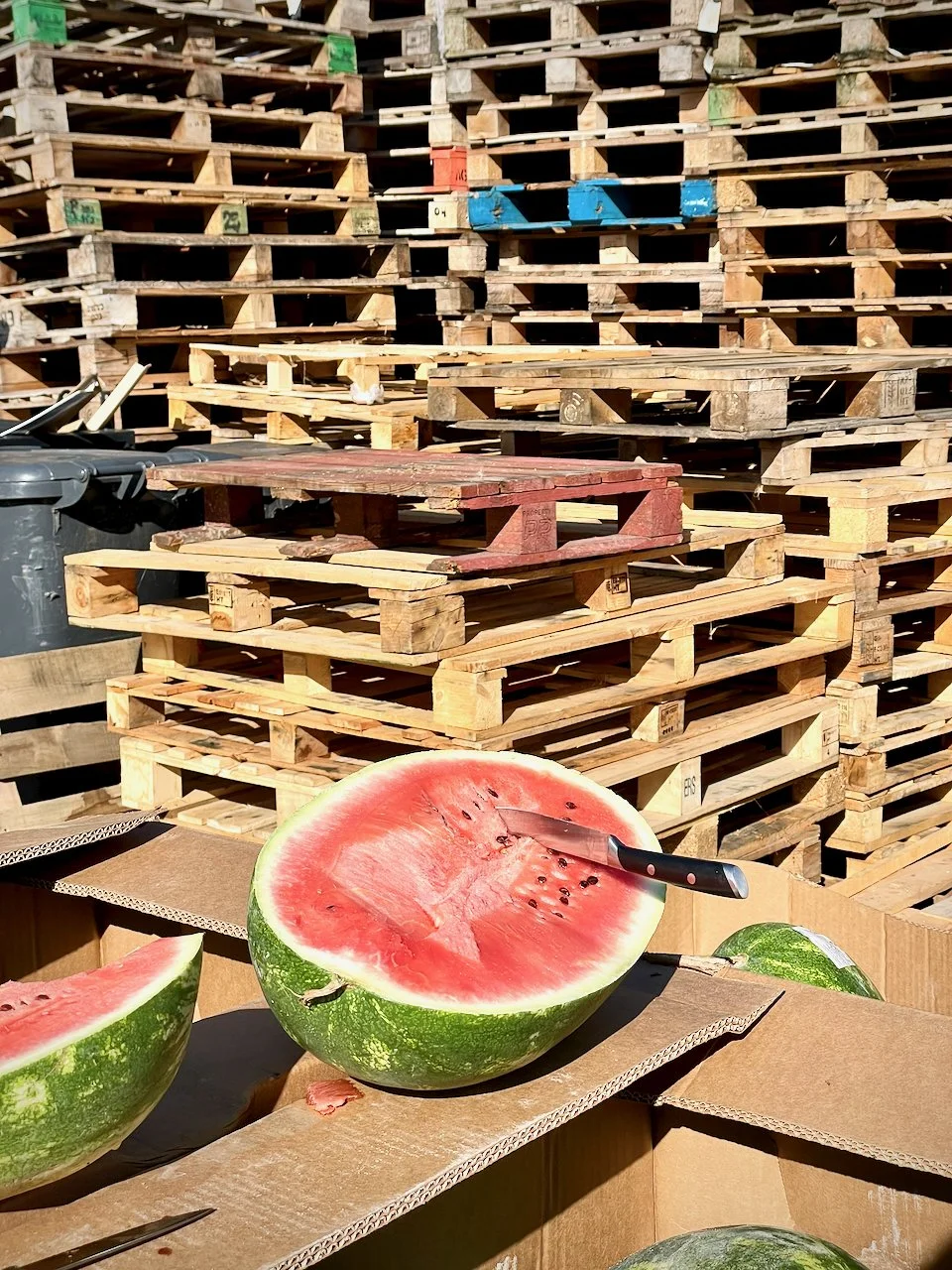 Paletten und eine aufgeschnittene Melone mit Messer im Gelände des Großmarkts in München