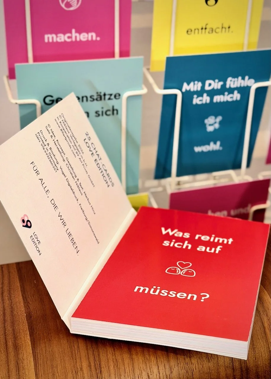 Buch mit 25 Postkarten mit dem Titel 25 Chat Cards. Love Edition. Man sieht die Postkarte "Was reimt sich auf müssen?"