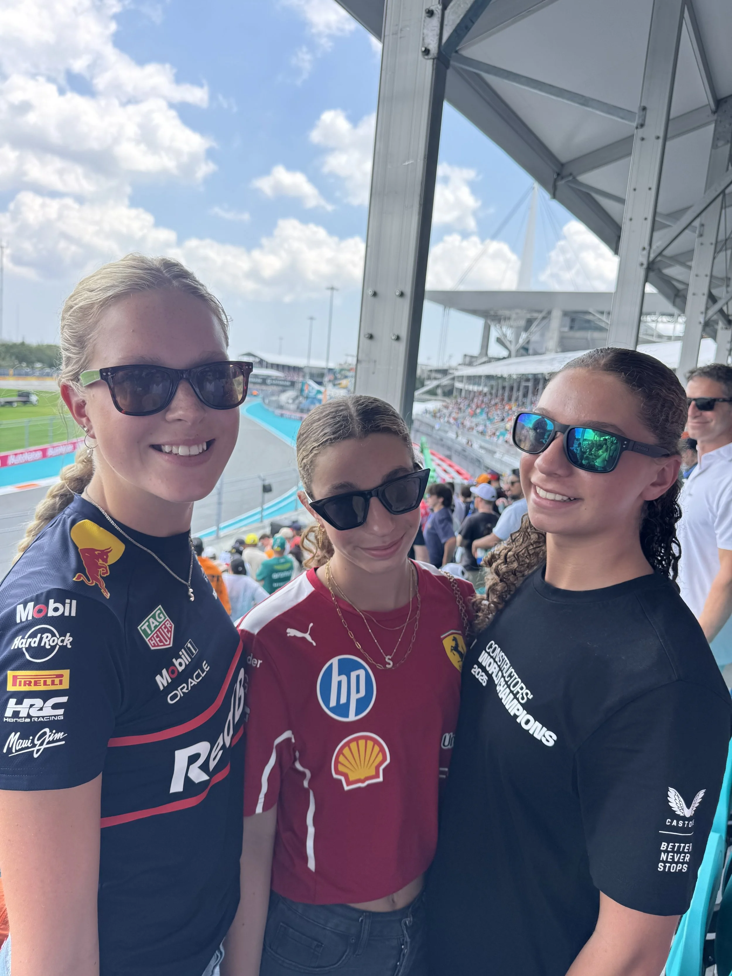 Family at Miami Grand Prix F1 race, daughters in racing team t-shirts in grandstand