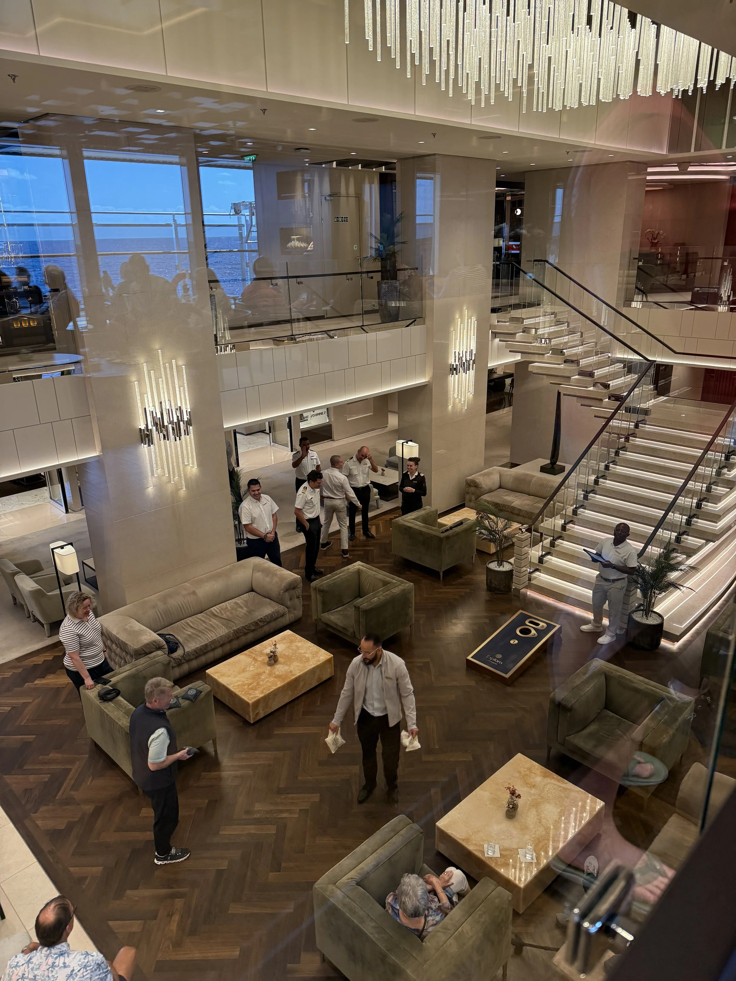 Guests and crew in the light-filled atrium lounge aboard Explora Journeys