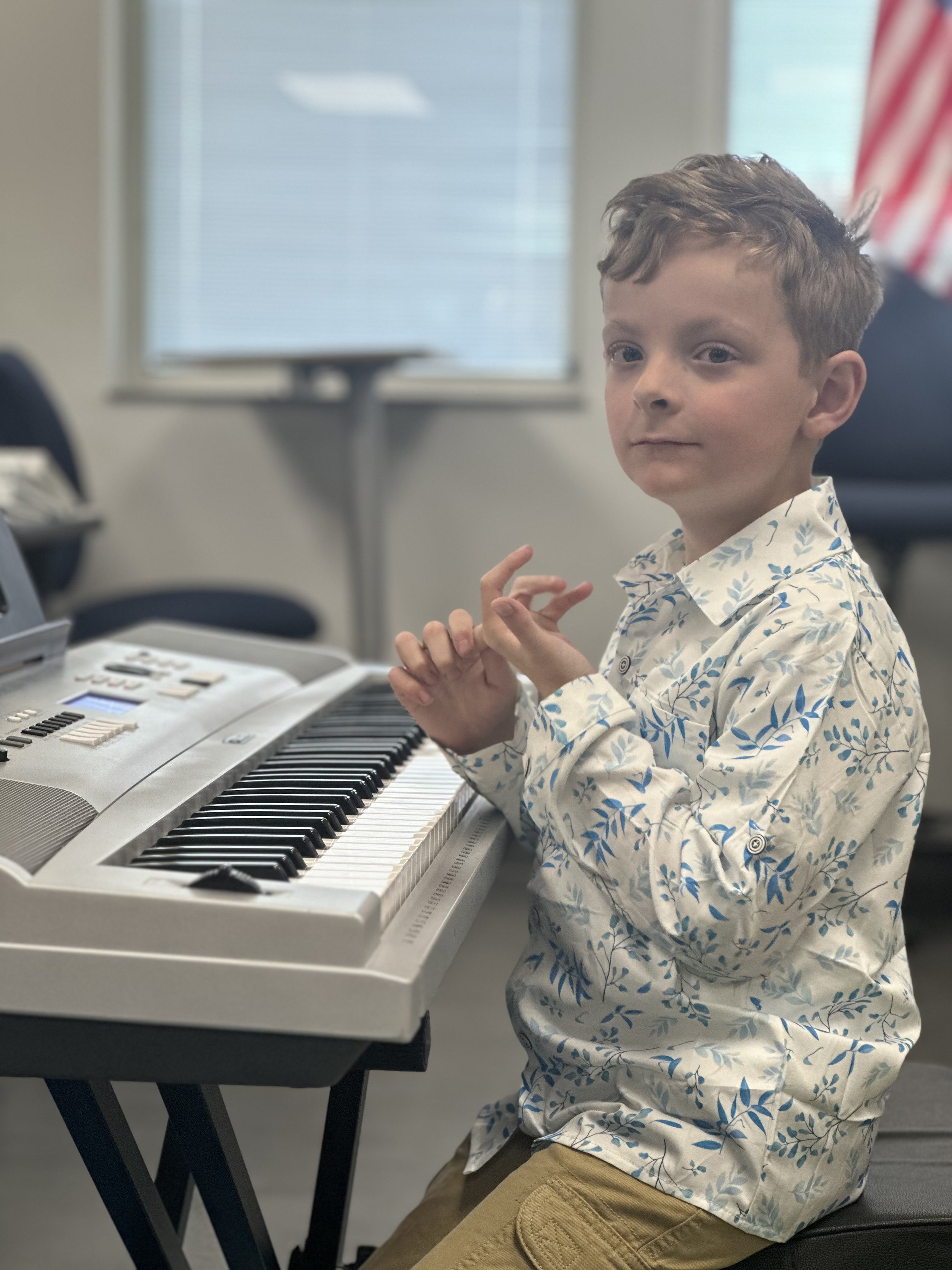 Young piano student playing a digital keyboard during a beginner music lesson.