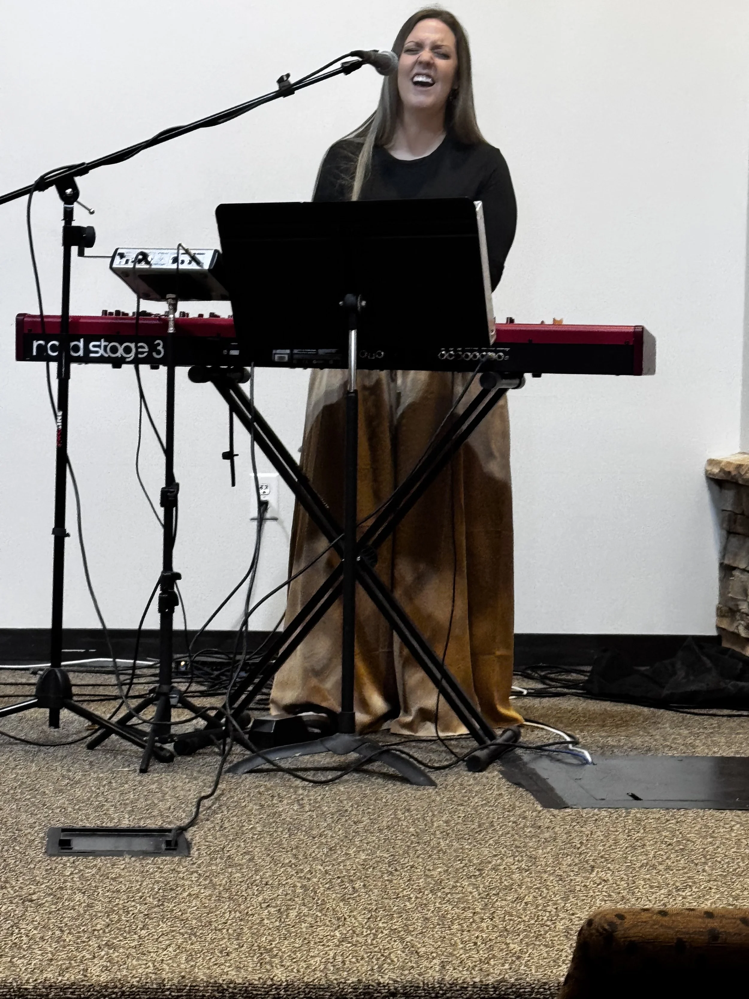 Brittany Brown leading worship while singing and playing keyboard during a live worship service.