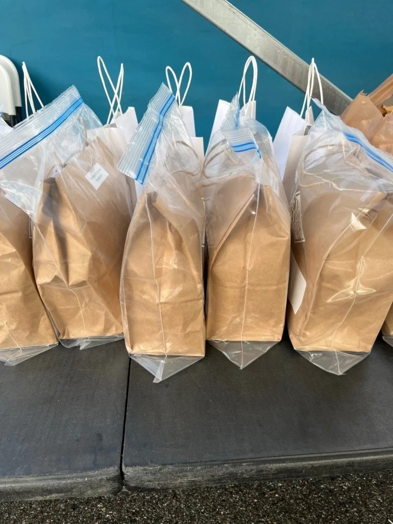 Multiple sealed plastic bags filled with brown paper or material, arranged in a row on a black surface.