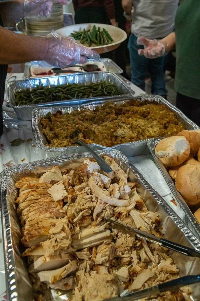 Buffet-style food with sliced turkey, green beans, a casserole, and dinner rolls.